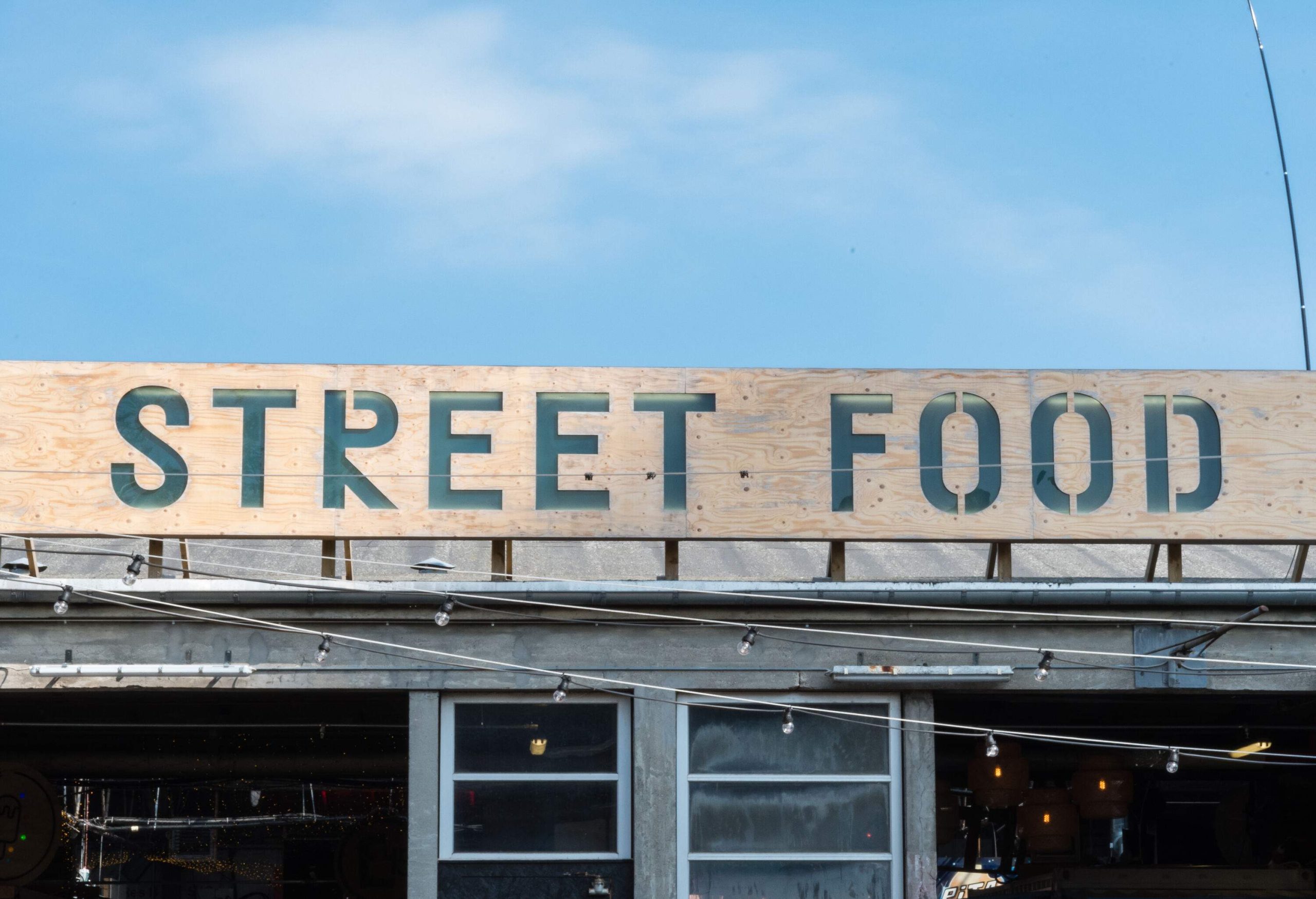 A wooden board on top of a roof with the words STREET FOOD inscribed on it.