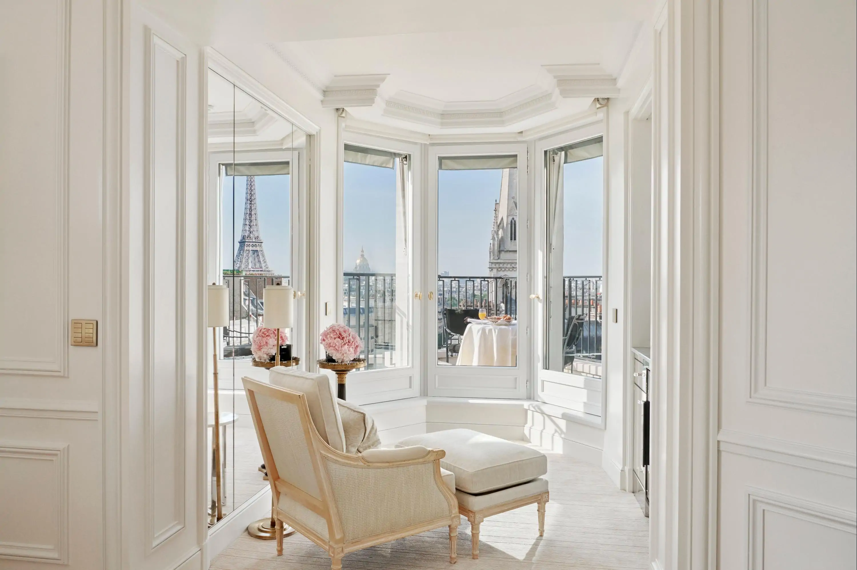 White hotel room with chaise longue and view over the Eiffel Tower