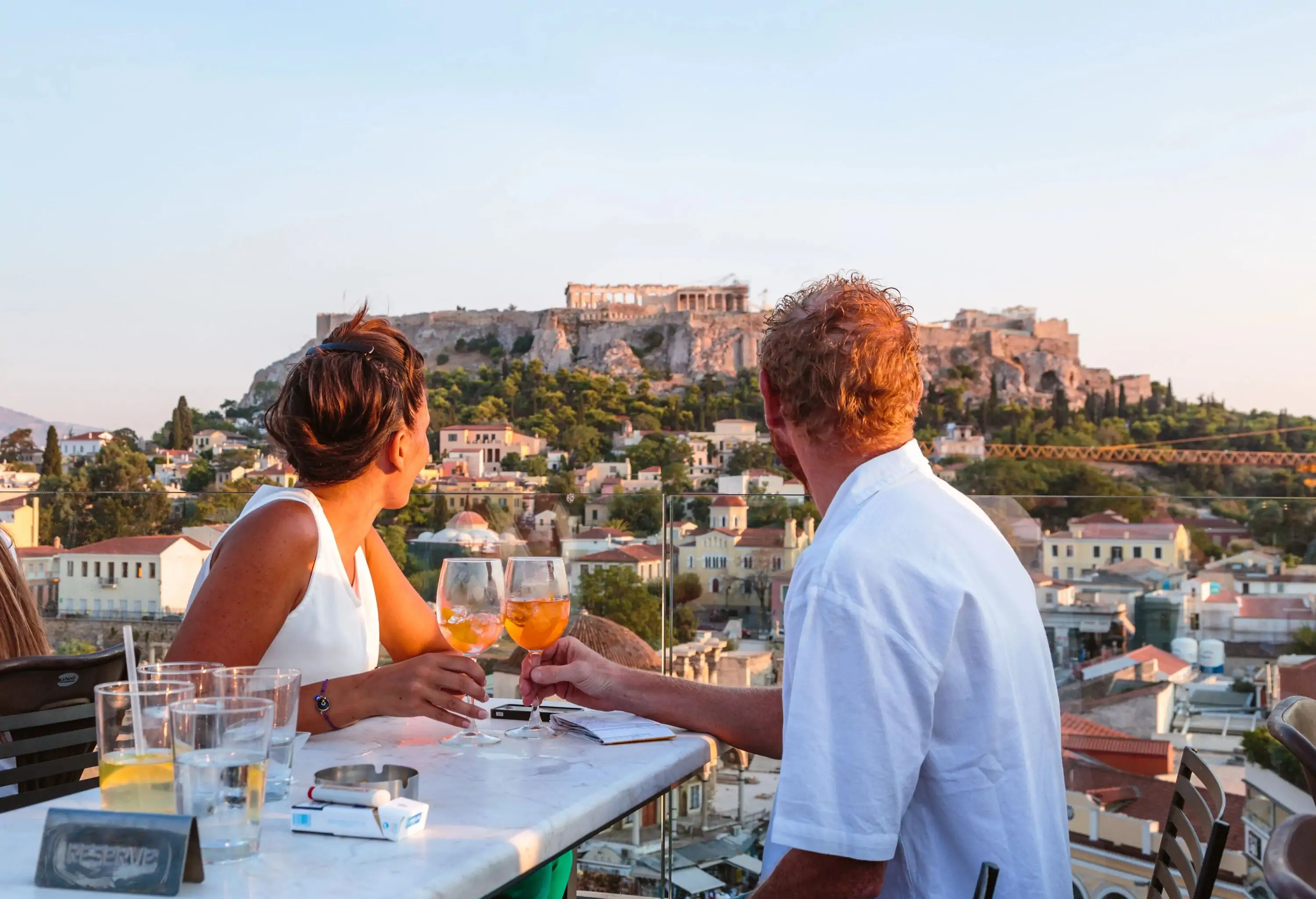 Couple drinking and enjoying the view of the Acropolis at sunset. Athens, Greece