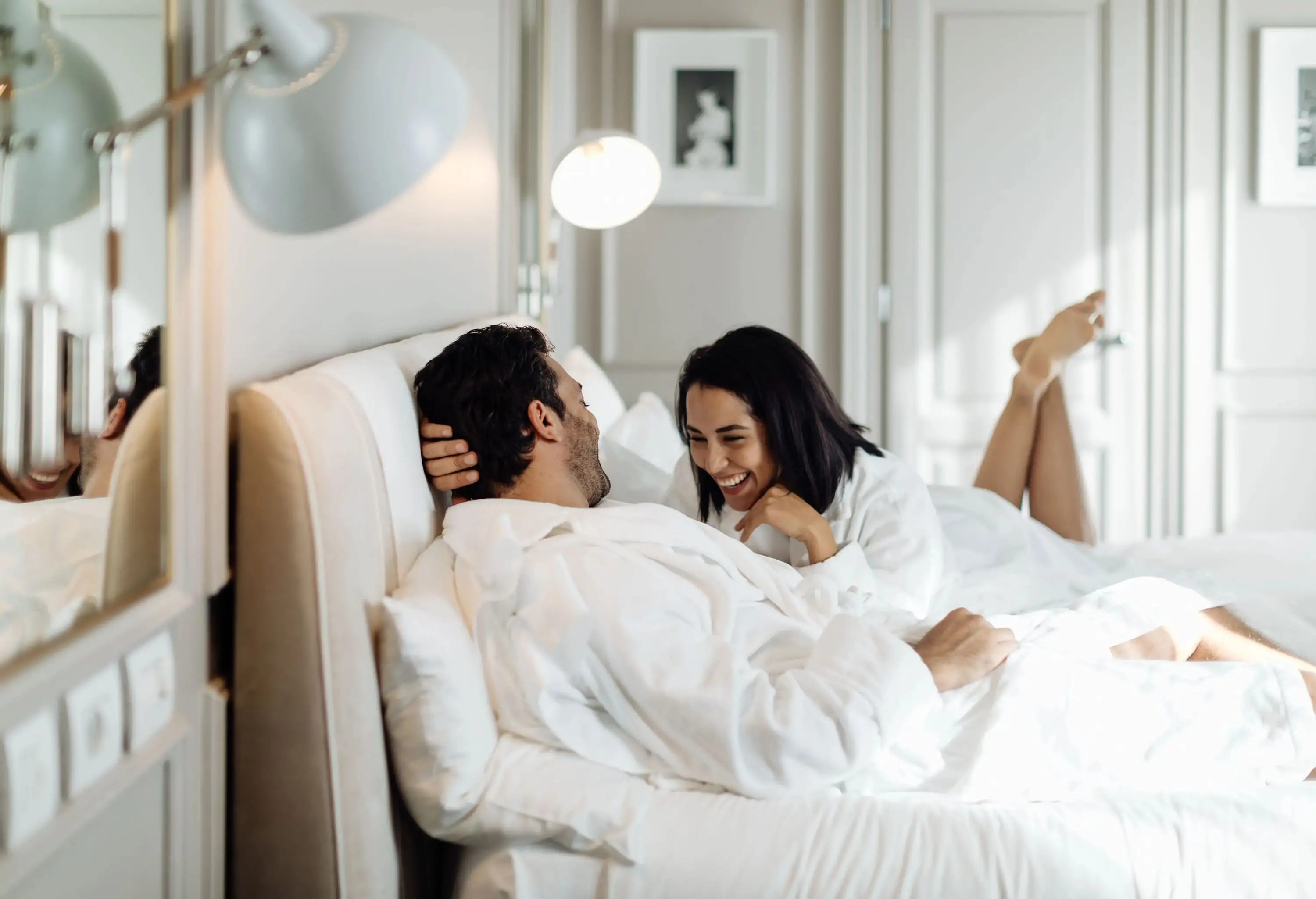 Couple laughing and relaxing in white luxury hotel suite