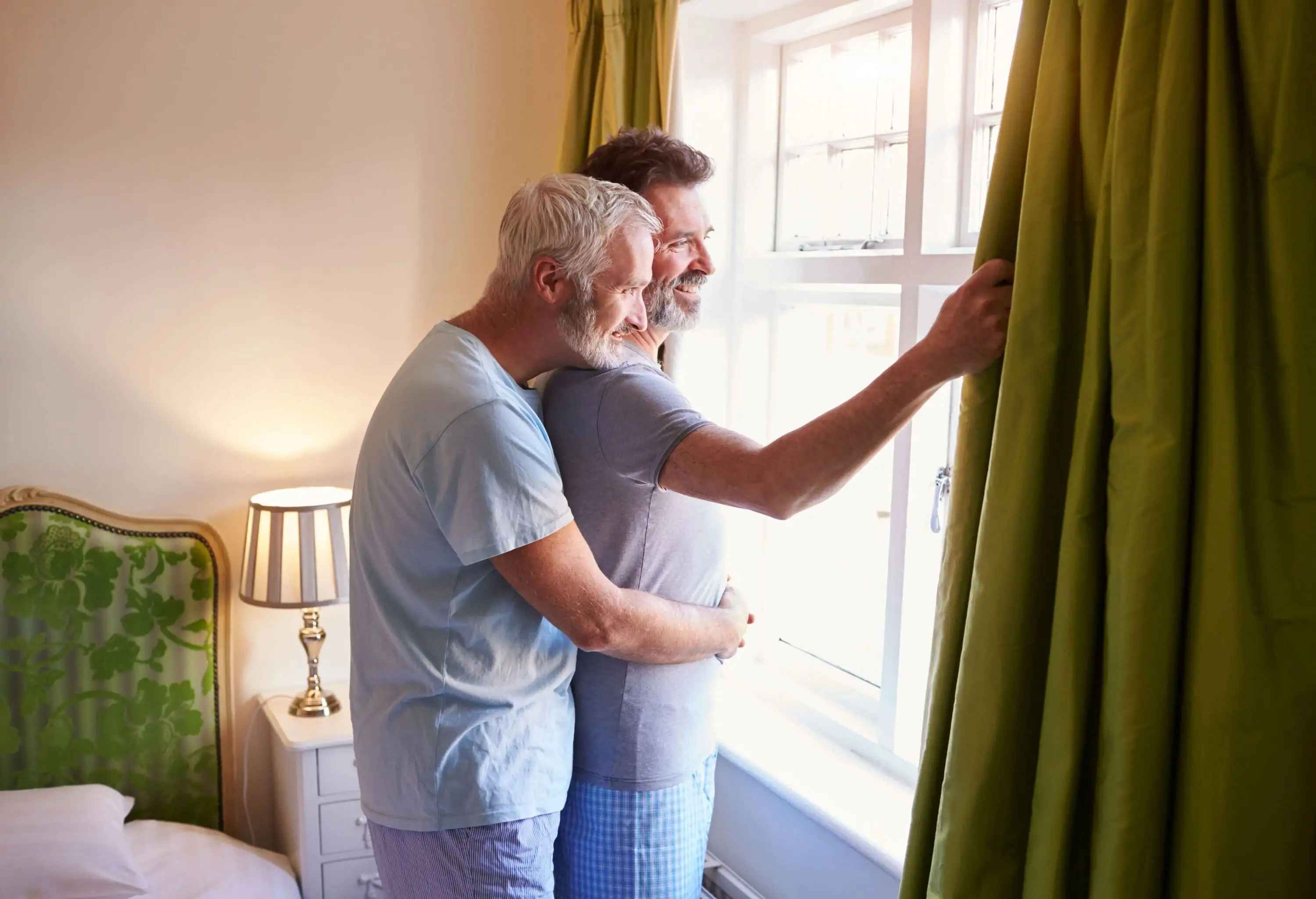 LGBTQ couple hugging by a window in a hotel room