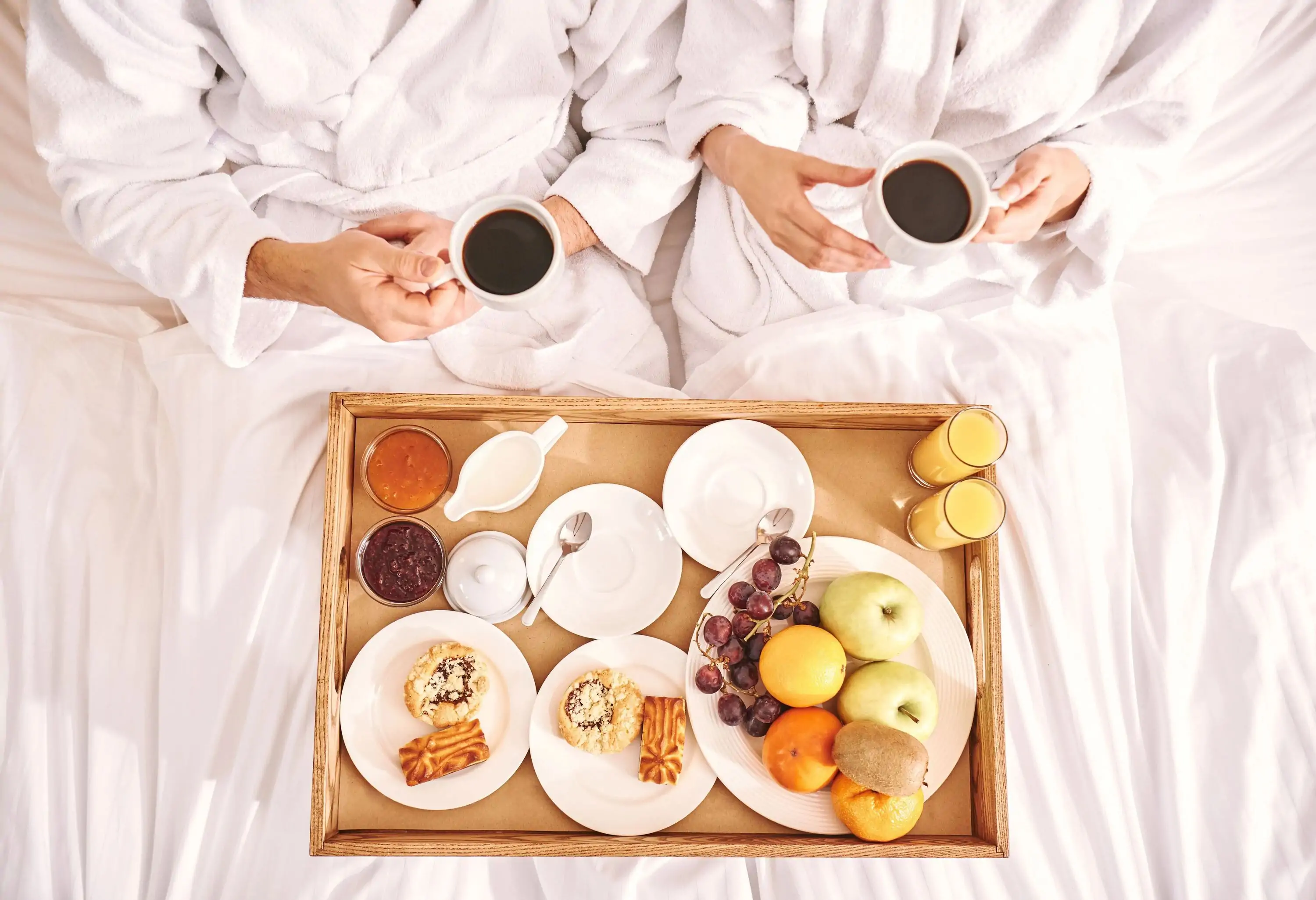 Fresh breakfast in room. Close-up of couple are eating in hotel room bed together. Love story. Top view