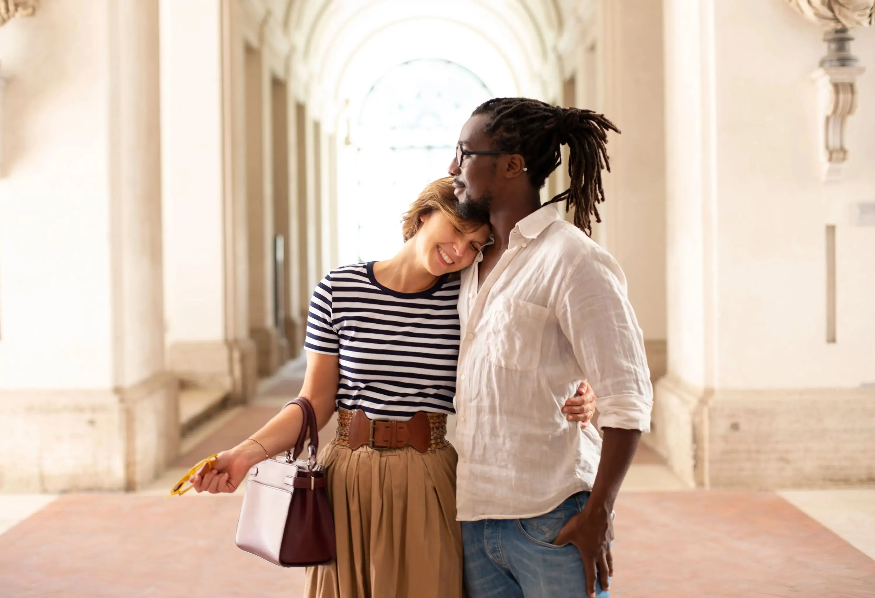 Multiracial couple hugging in the hallway of museum or historical place