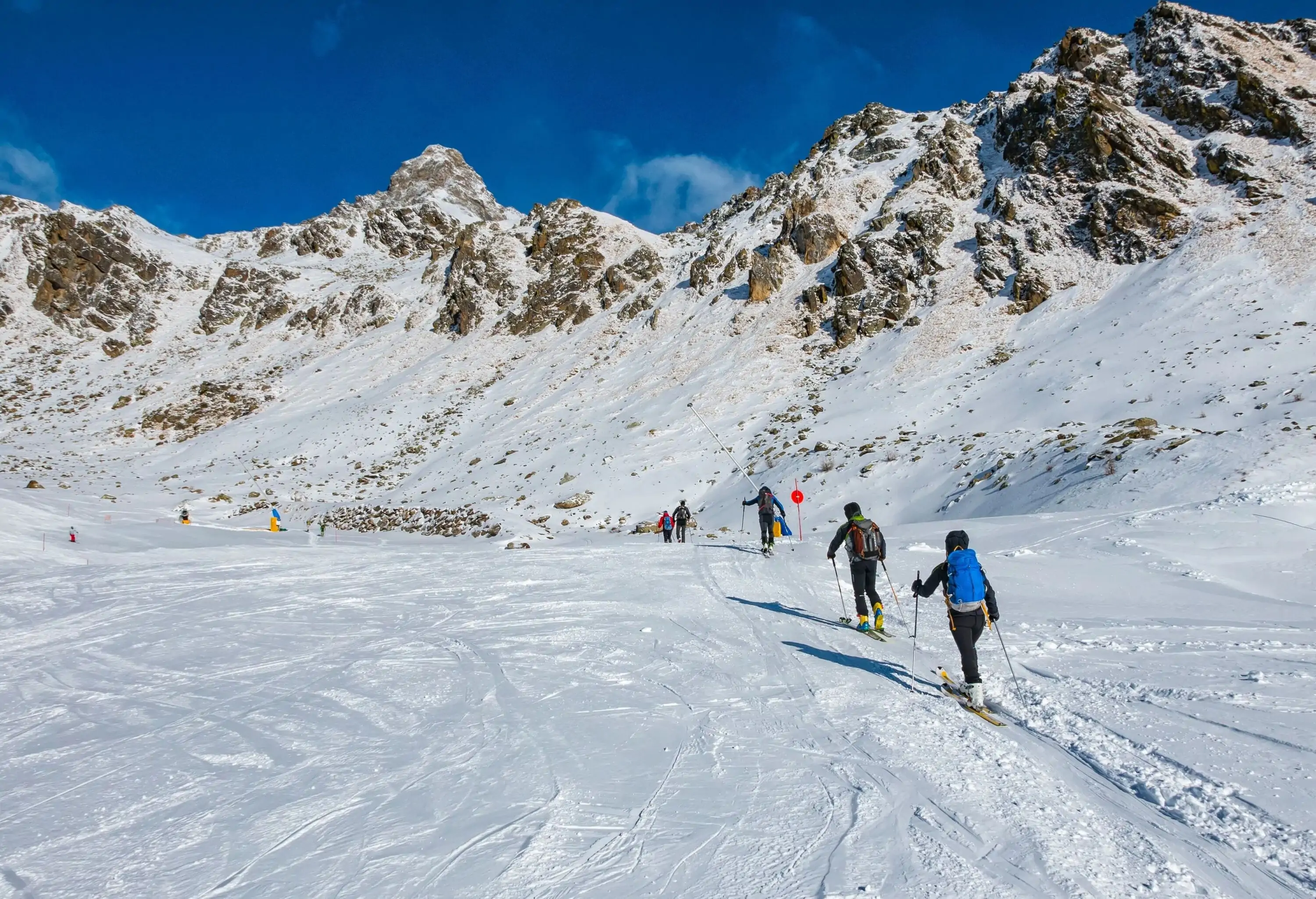 People snowshoeing on the snow land beneath the mountains covered in snow.