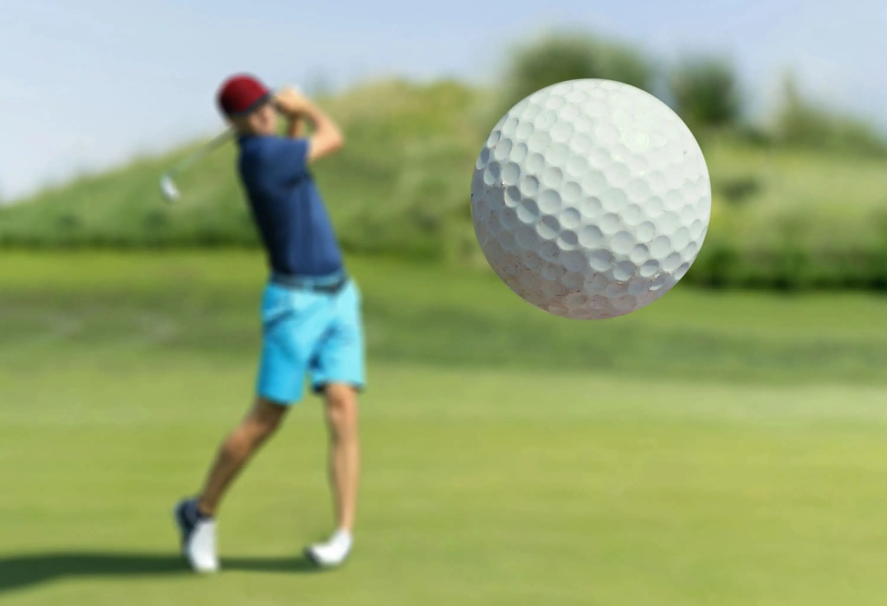 A focused golfer at a club skillfully strikes the ball, which soars through the foreground.