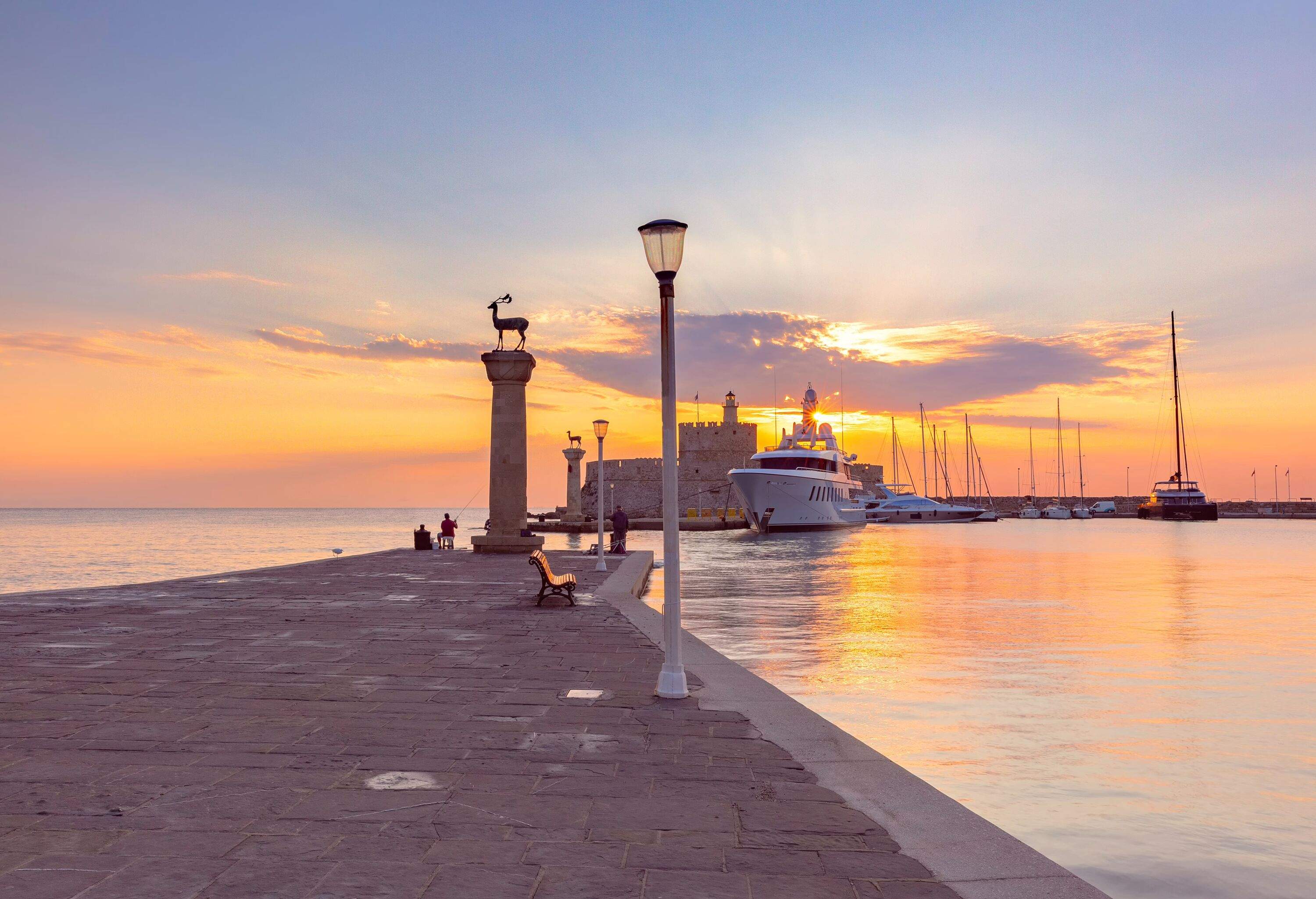 Mandraki Harbor with iconic deer statue on column and St Nicholas Fortress in Rhodes, Greece