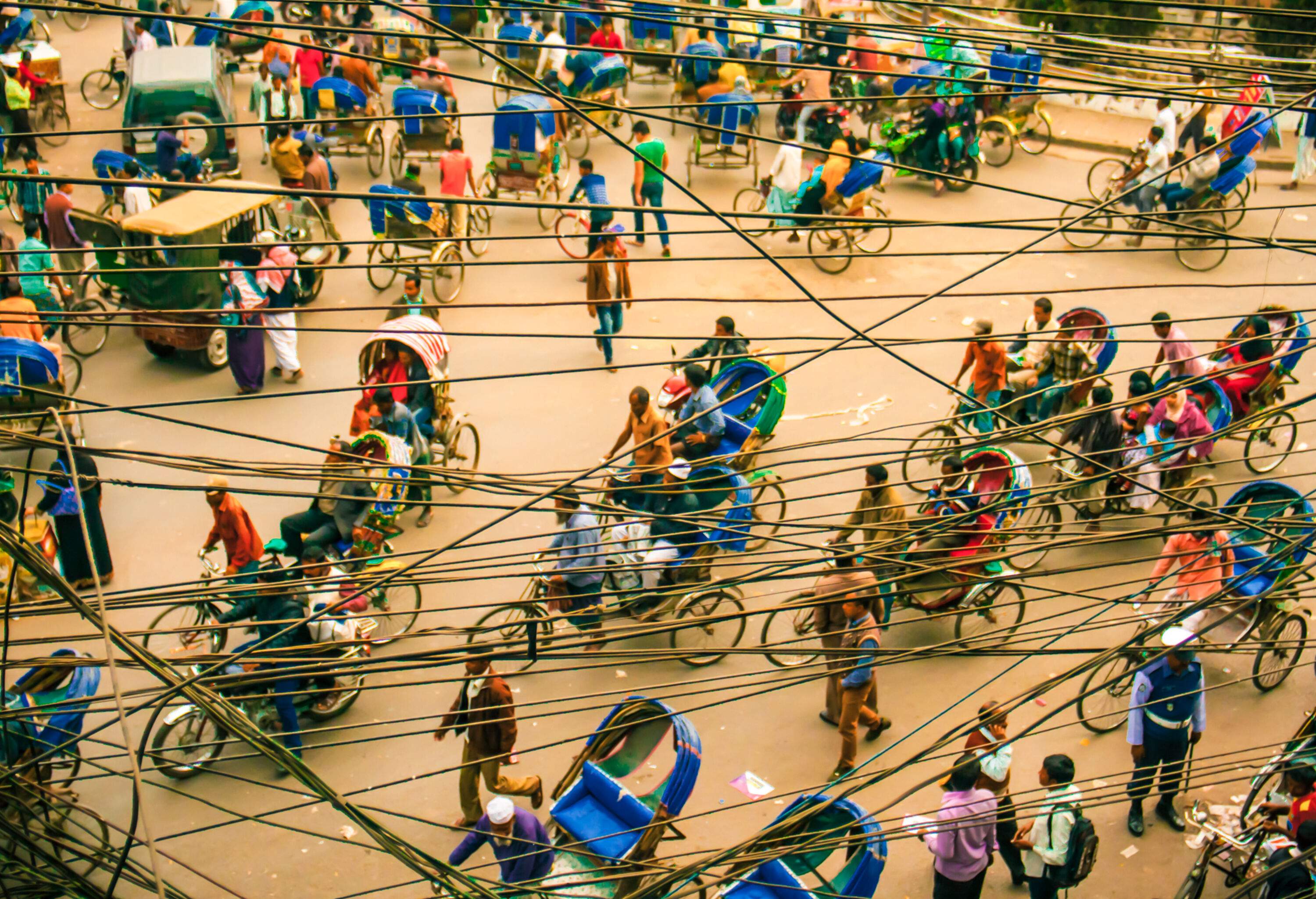 Rickshaws scattered over a busy street, with power lines dangling overhead.