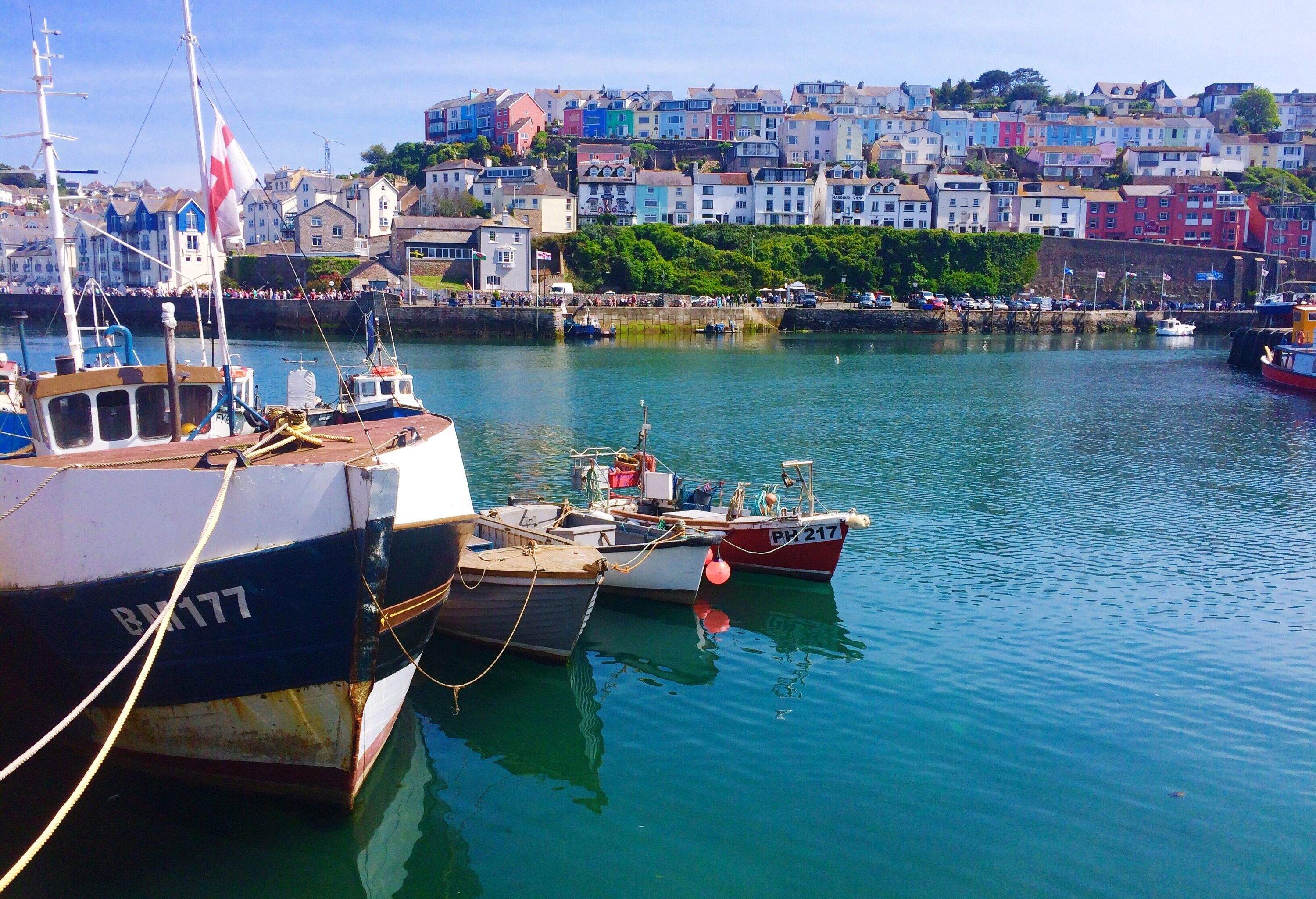 Boats moored in the harbour of a coastal town with colourful and classic buildings.