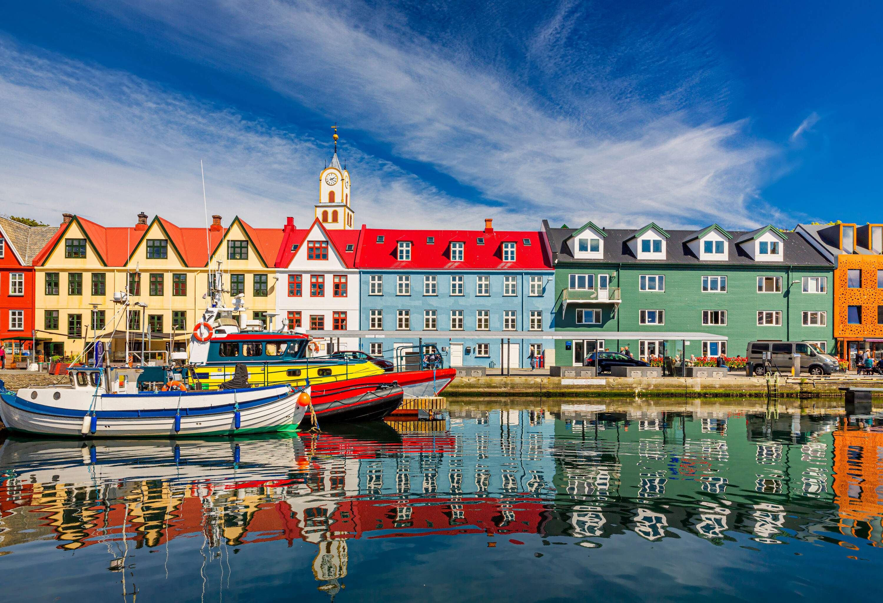 Brightly painted houses in front of a harbour with fishing boats.