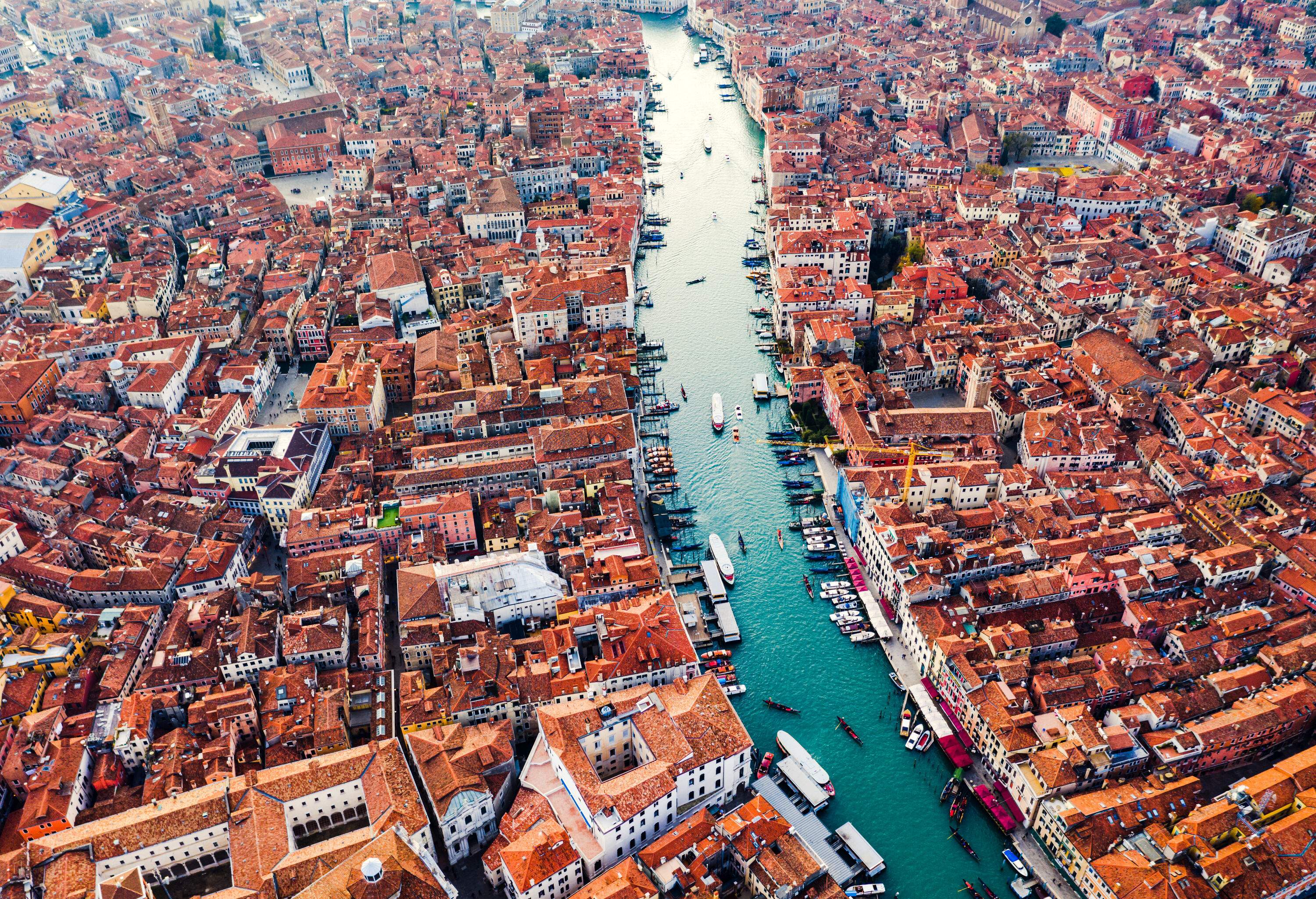 A water canal with anchored and cruising boats across a cluster of city buildings.