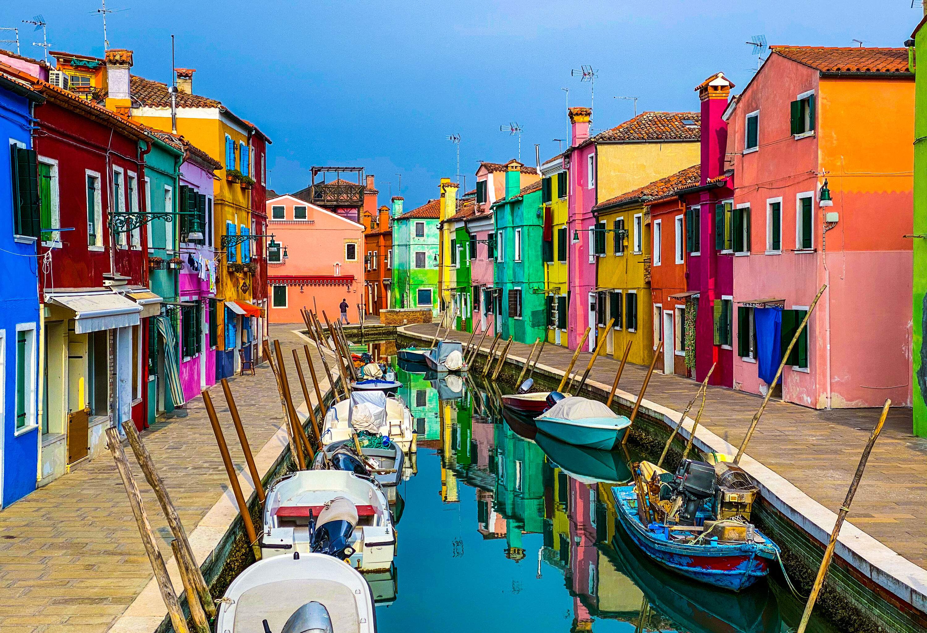 Small motorboats docked in a canal between vibrantly painted houses.