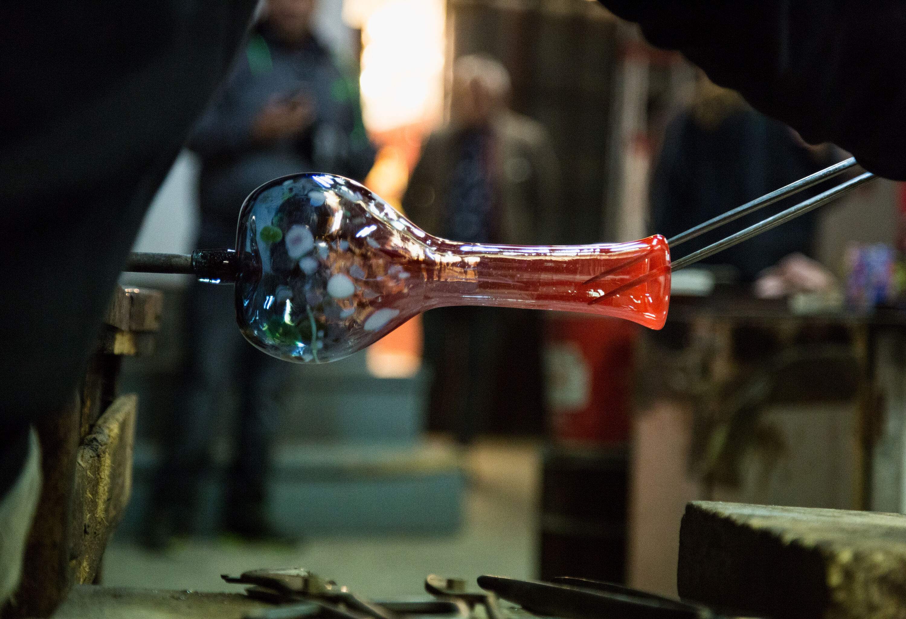 An artisan skillfully crafts a beautiful glass vase with precision and expertise.