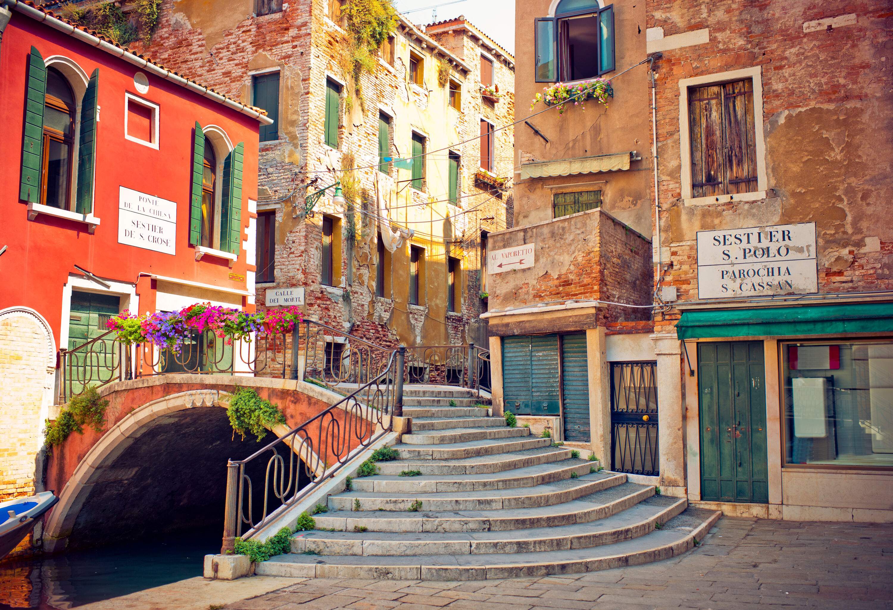 A canal runs through a charming town, flanked by beautiful buildings and crossed by a quaint bridge.