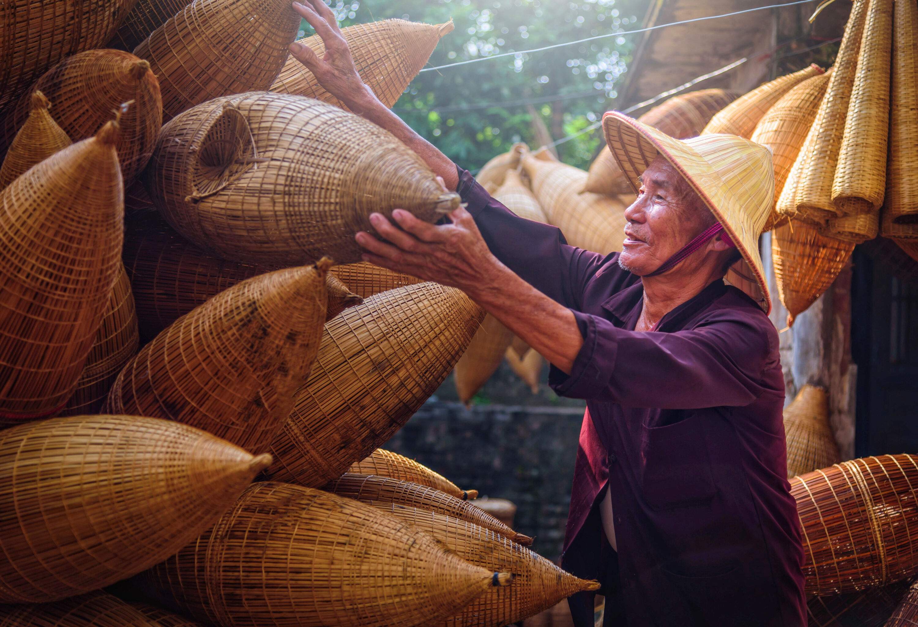 A Vietnamese fisherman diligently arranges and stacks traditional basketry used for fishing equipment.