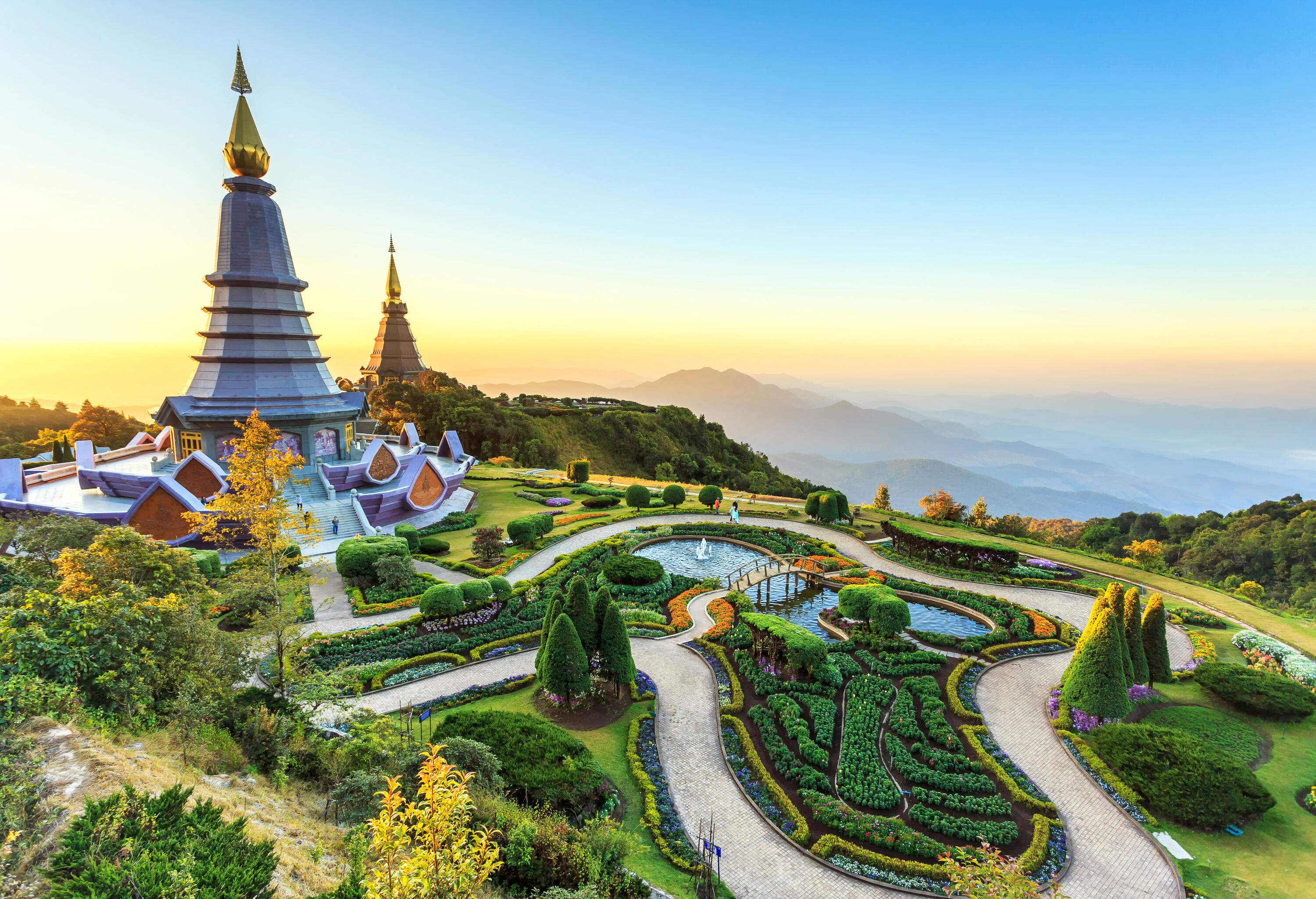 Two adjacent spectacular temples on a lush mountaintop with a beautiful landscape at sunset.