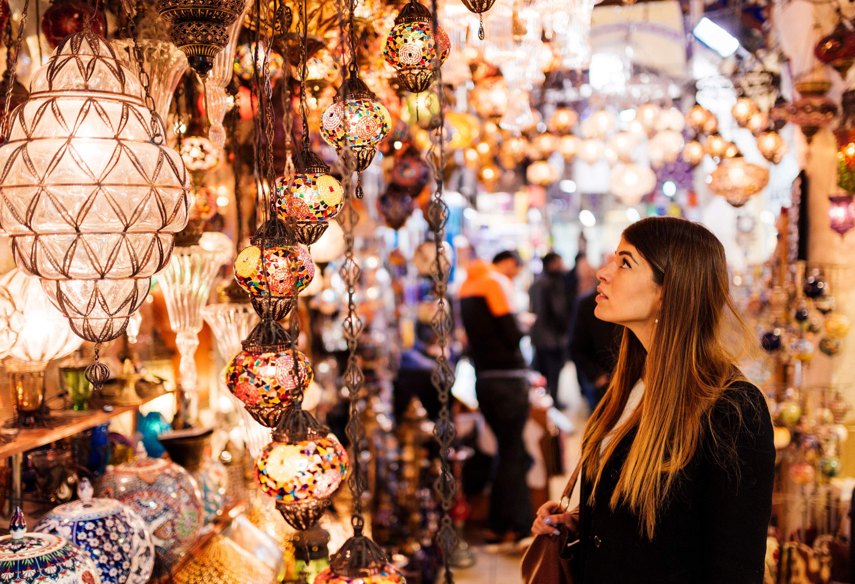 A beautiful woman gazing at the vibrant display of colourful lights on a market stall.