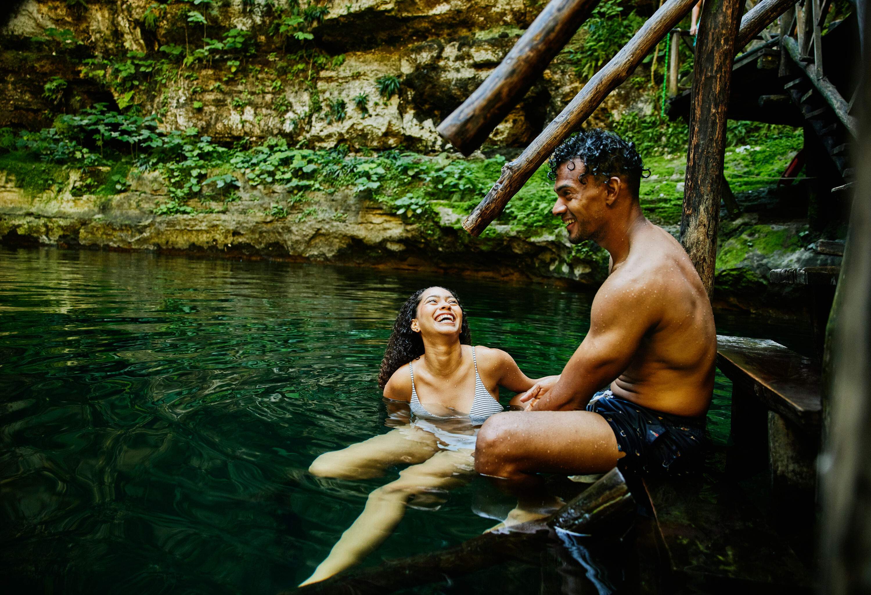 Man and woman sitting on the ledge of staircase in a cenote in Mexico's Yucatan