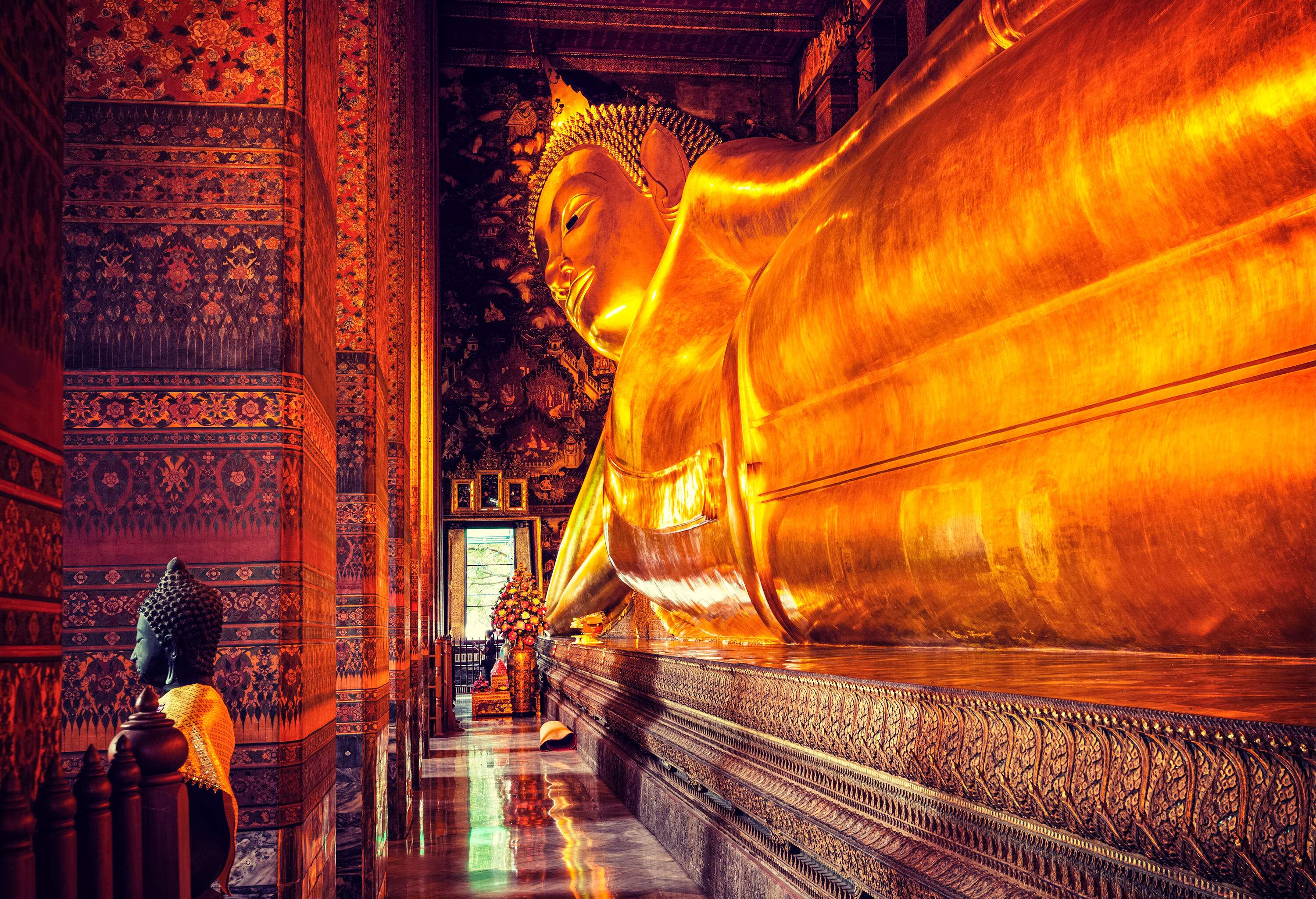 The gold-plated Reclining Buddha of Wat Pho housed in a temple with eclectic wall patterns.