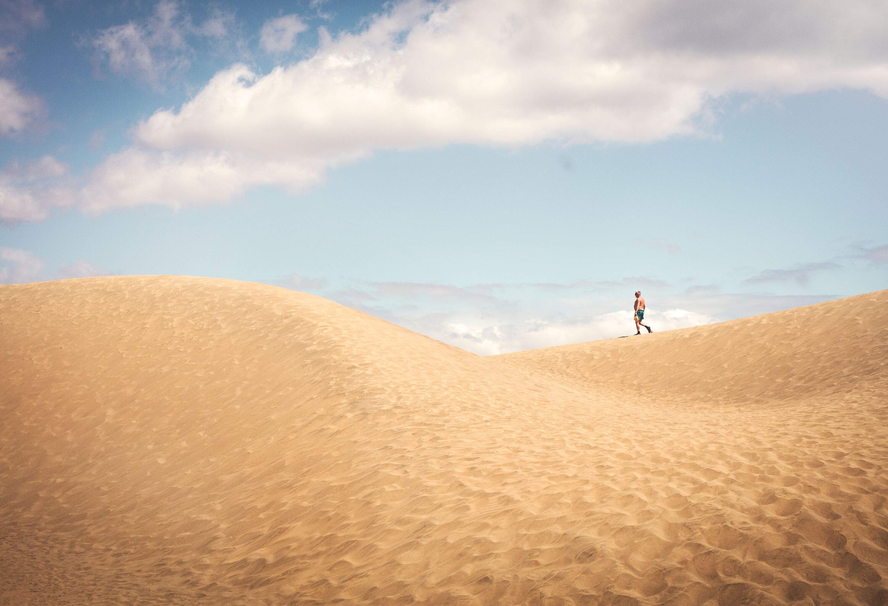 A person walking on deserted sand dunes.