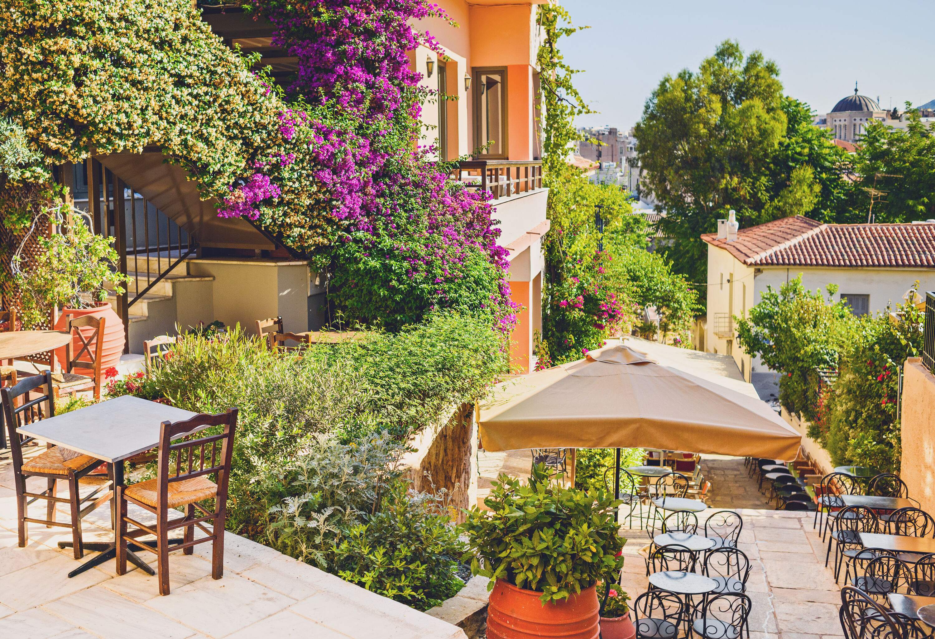 Tables and chairs outside the building that is covered in lush greenery and colourful flowers.