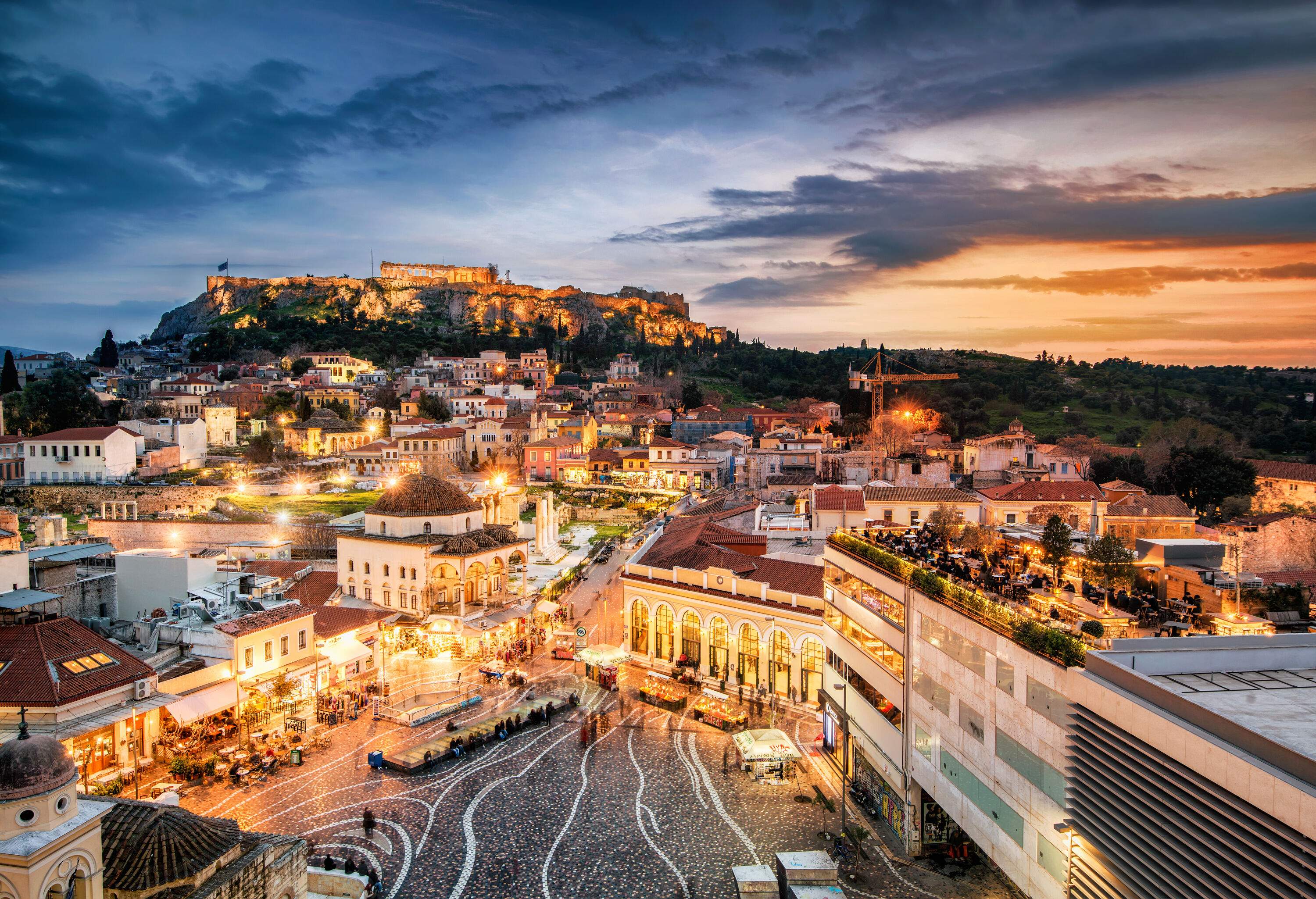 Illuminated night view of Athens crowded with tourists and locals overlooking the famous Greek monumental complex.