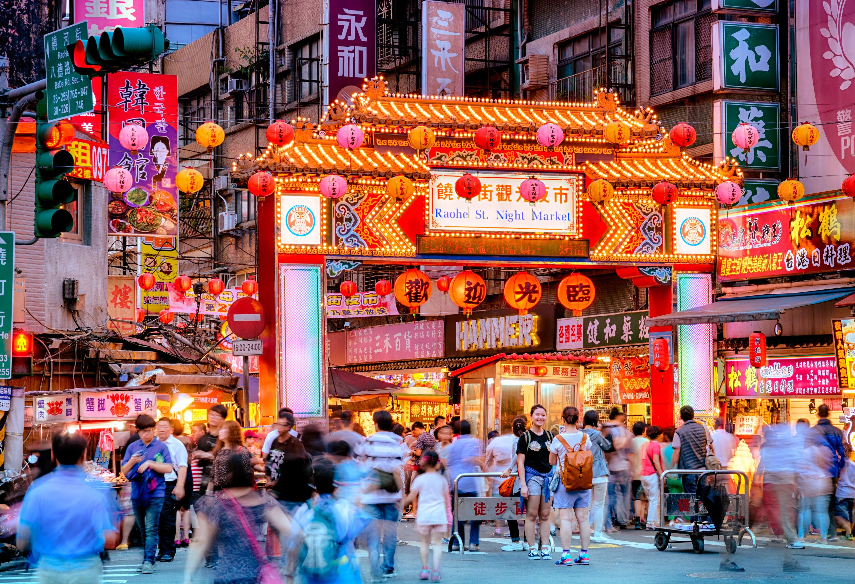 A brightly lit and bustling colourful night market adorned with Chinese lanterns.