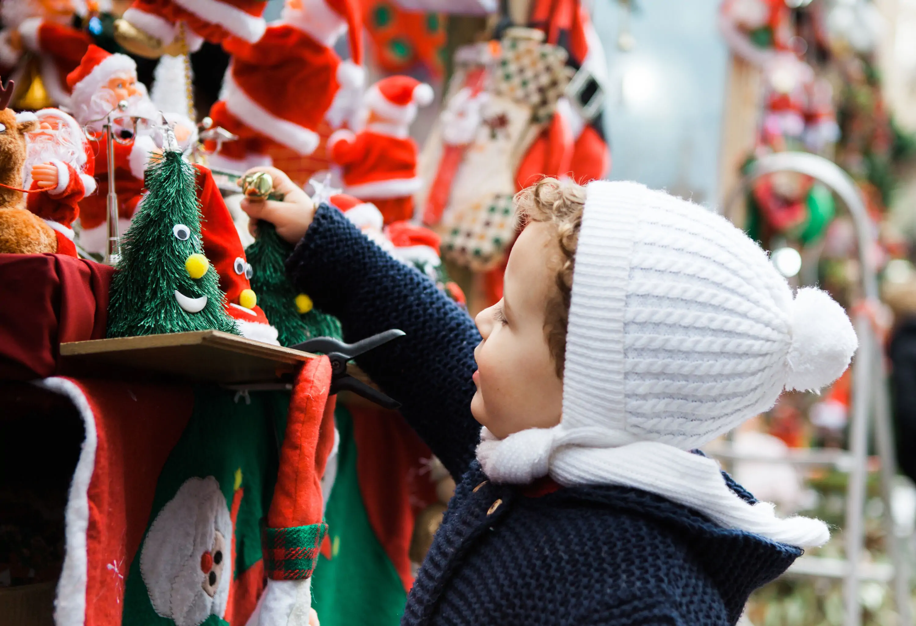 A boy wearing a navy jacket and white knitted hat grabs a toy souvenir on display.