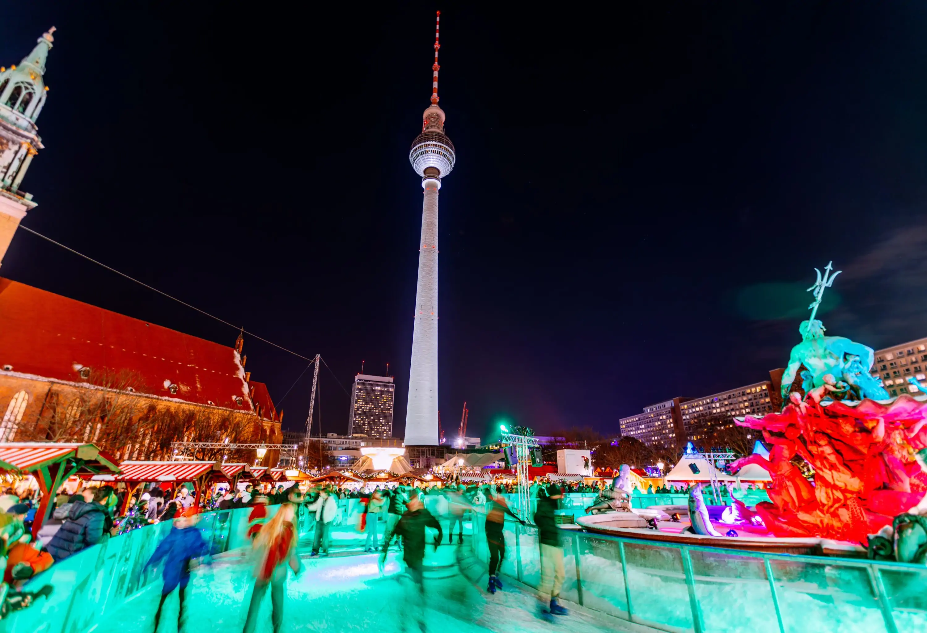 People ice-skating at the Rotes Rathaus Christmas Market with Berlin TV Tower in the background, Germany