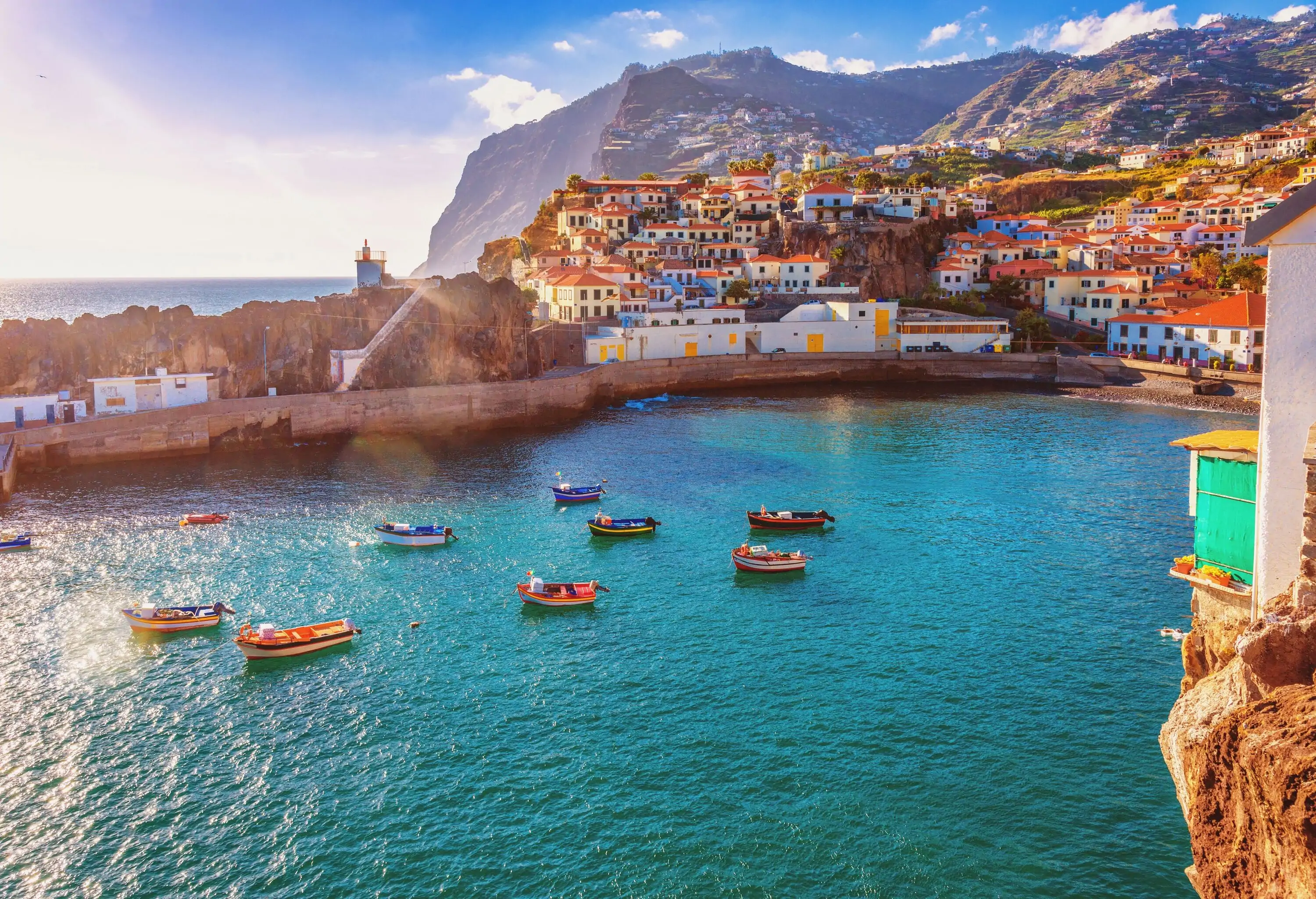 Small colourful boats moored on the harbour along compact houses ascending to the mountaintop.