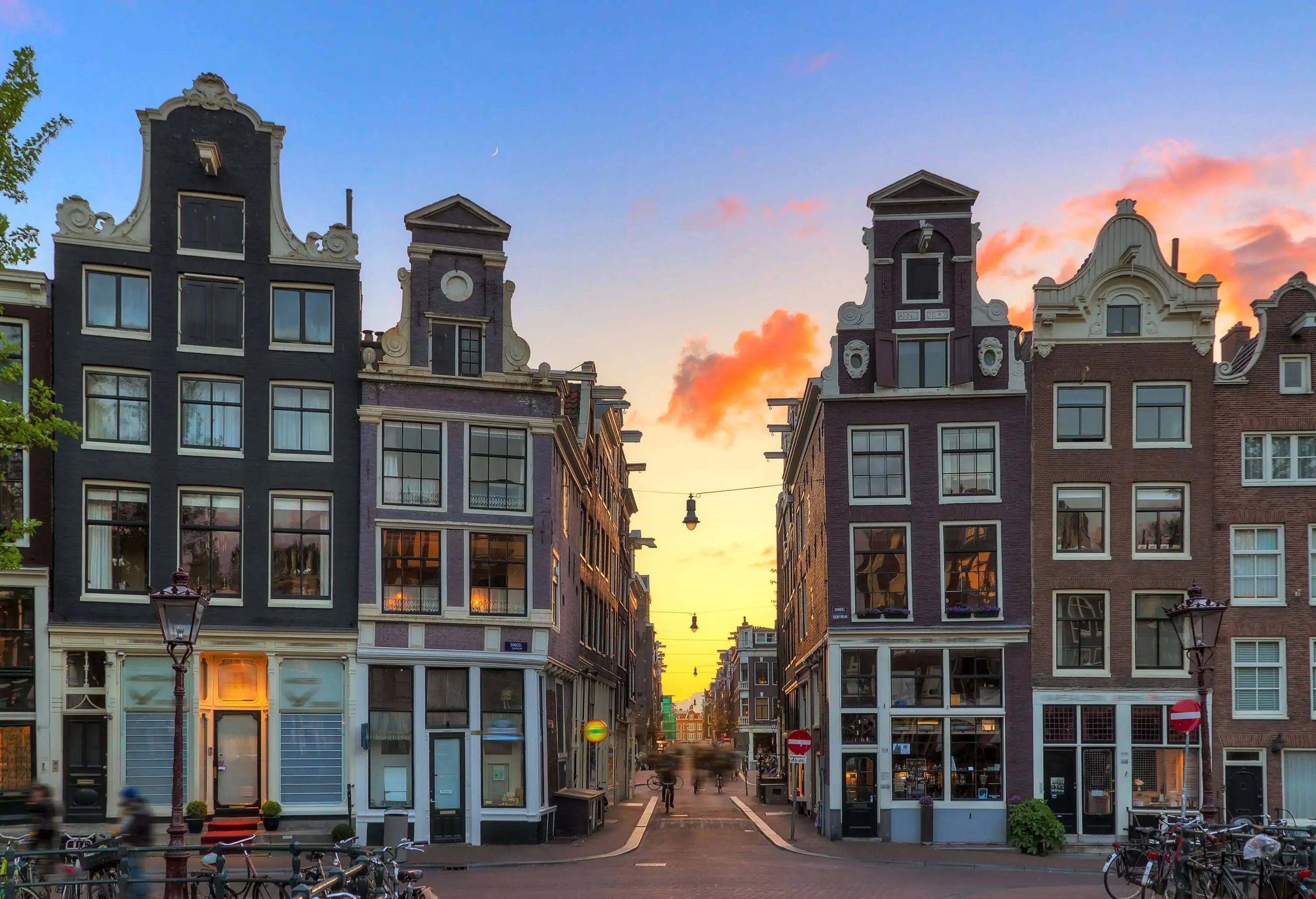 People are in motion in the narrow street in the middle of the traditional canal houses of Amsterdam, Netherlands.