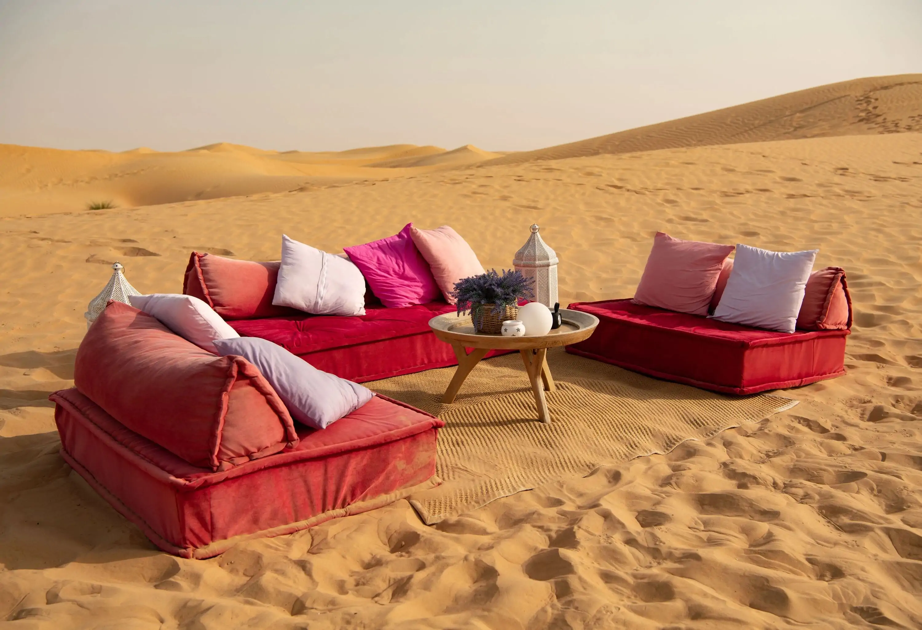 A mat in the desert with three couches around a coffee table.