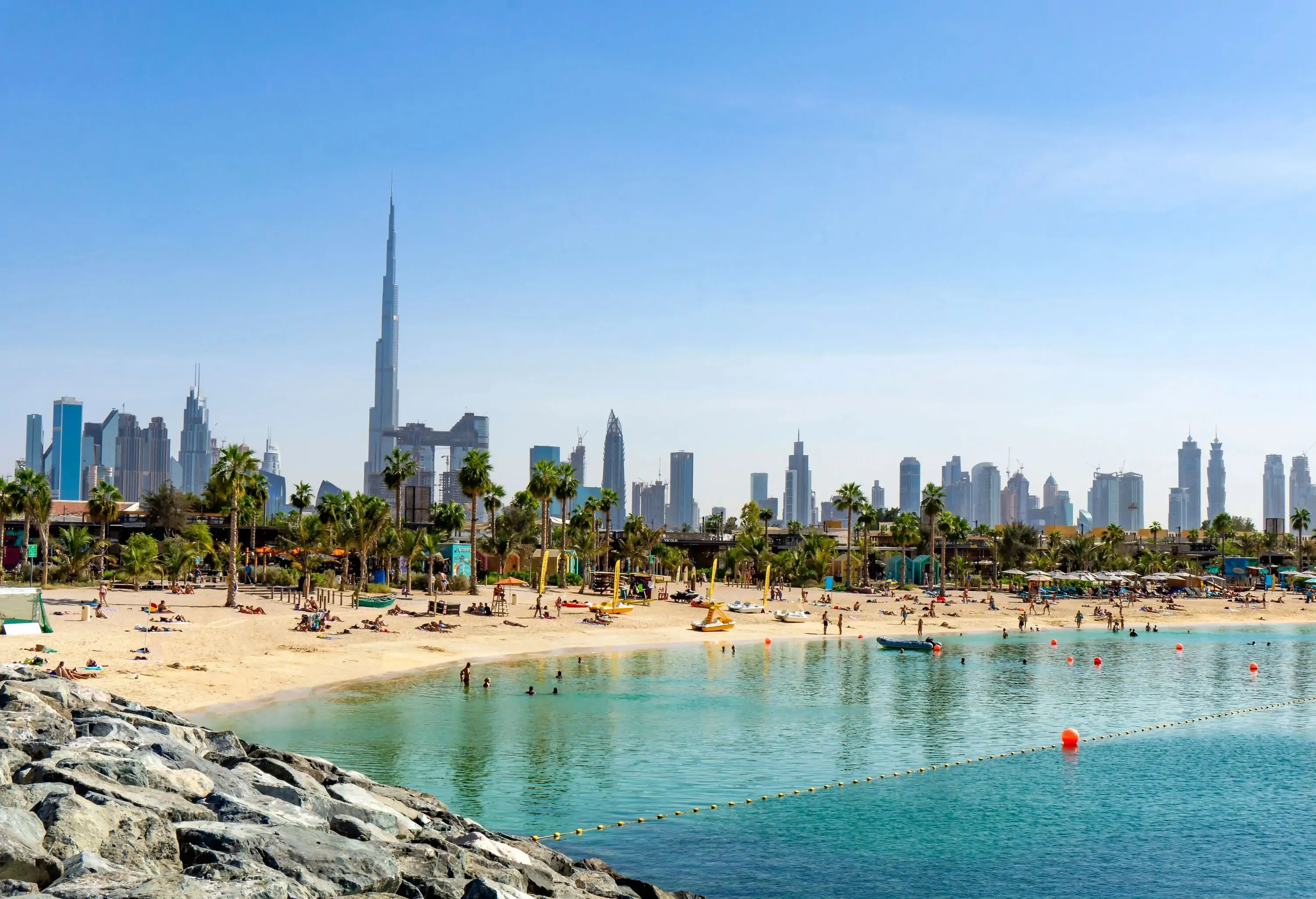 The skyline is stunning, with the beach full of people and the skyscrapers in the distance.