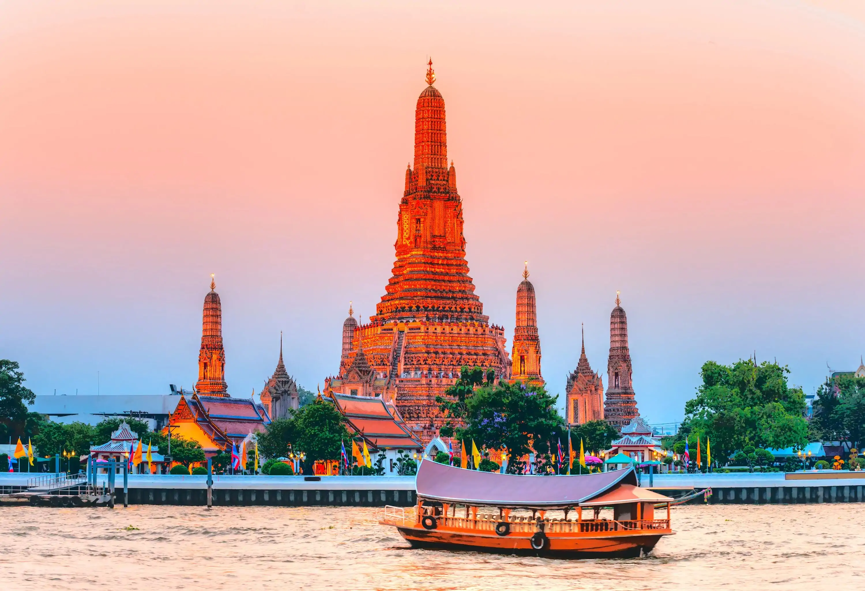 A passenger boat sailing along the river with distant views of the enormous Wat Arun temple.