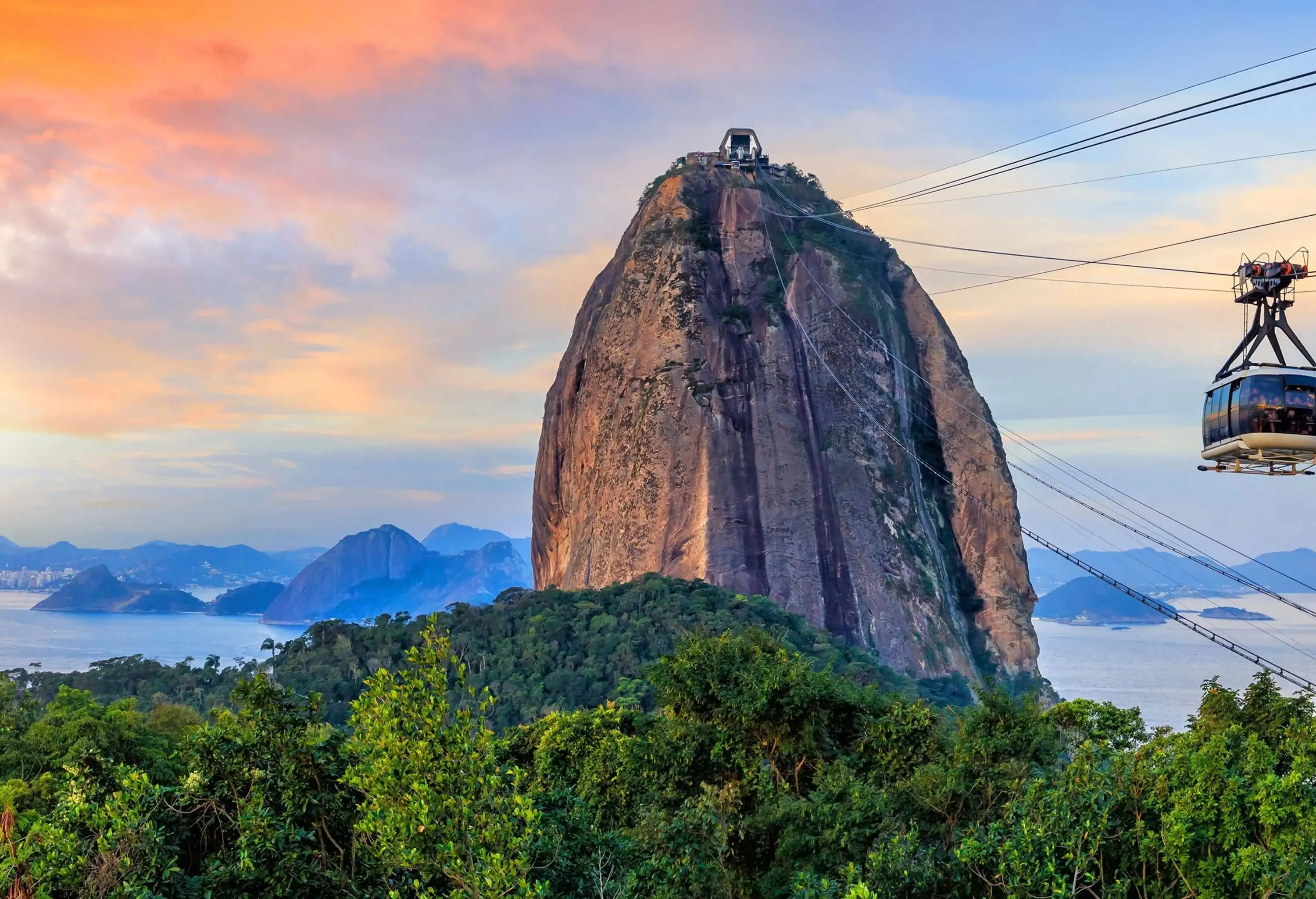 A cable car that reaches up to the top of a tall rock structure overlooking the sea.