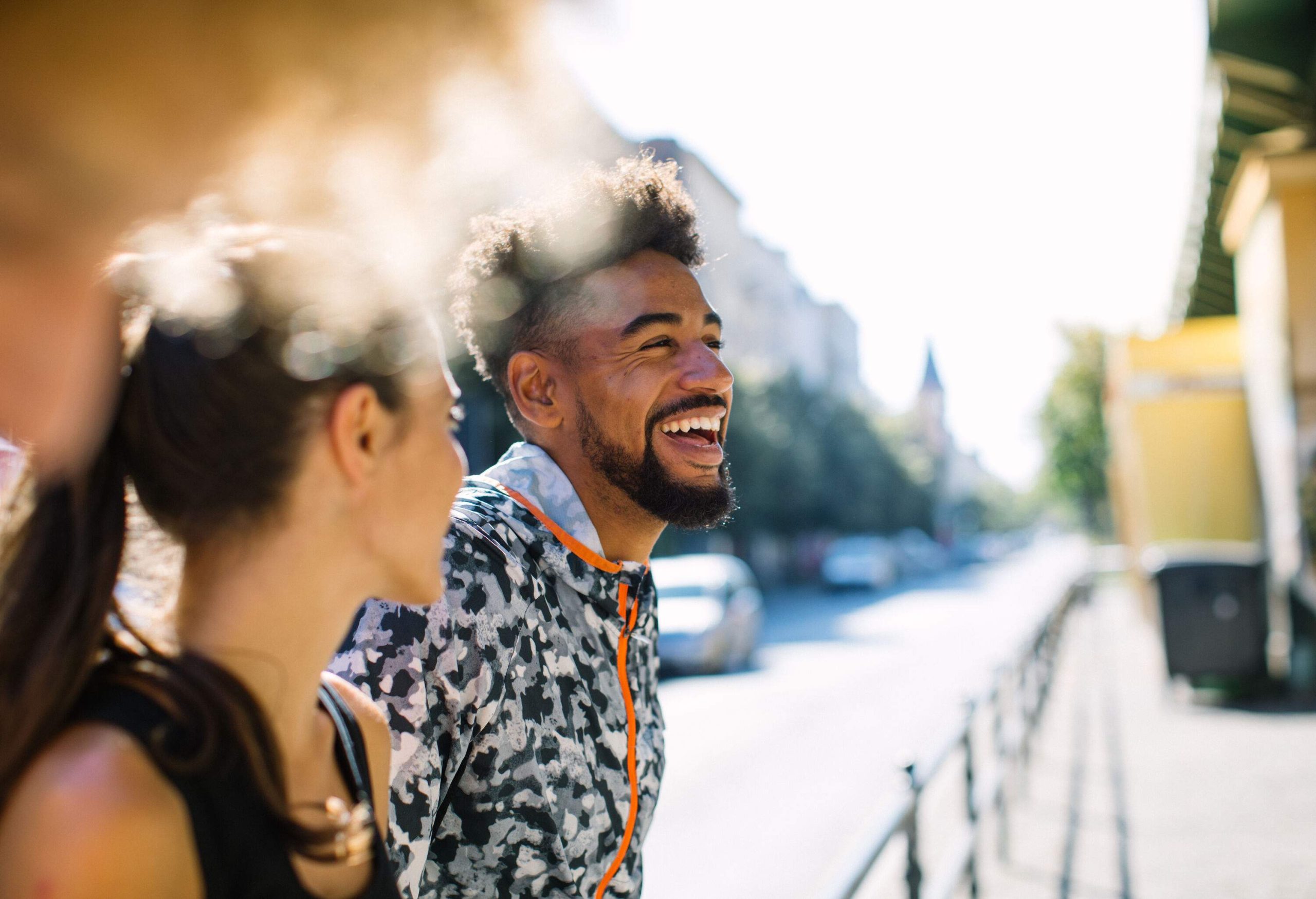 A man in a track jacket laughing while hanging out with his friends.