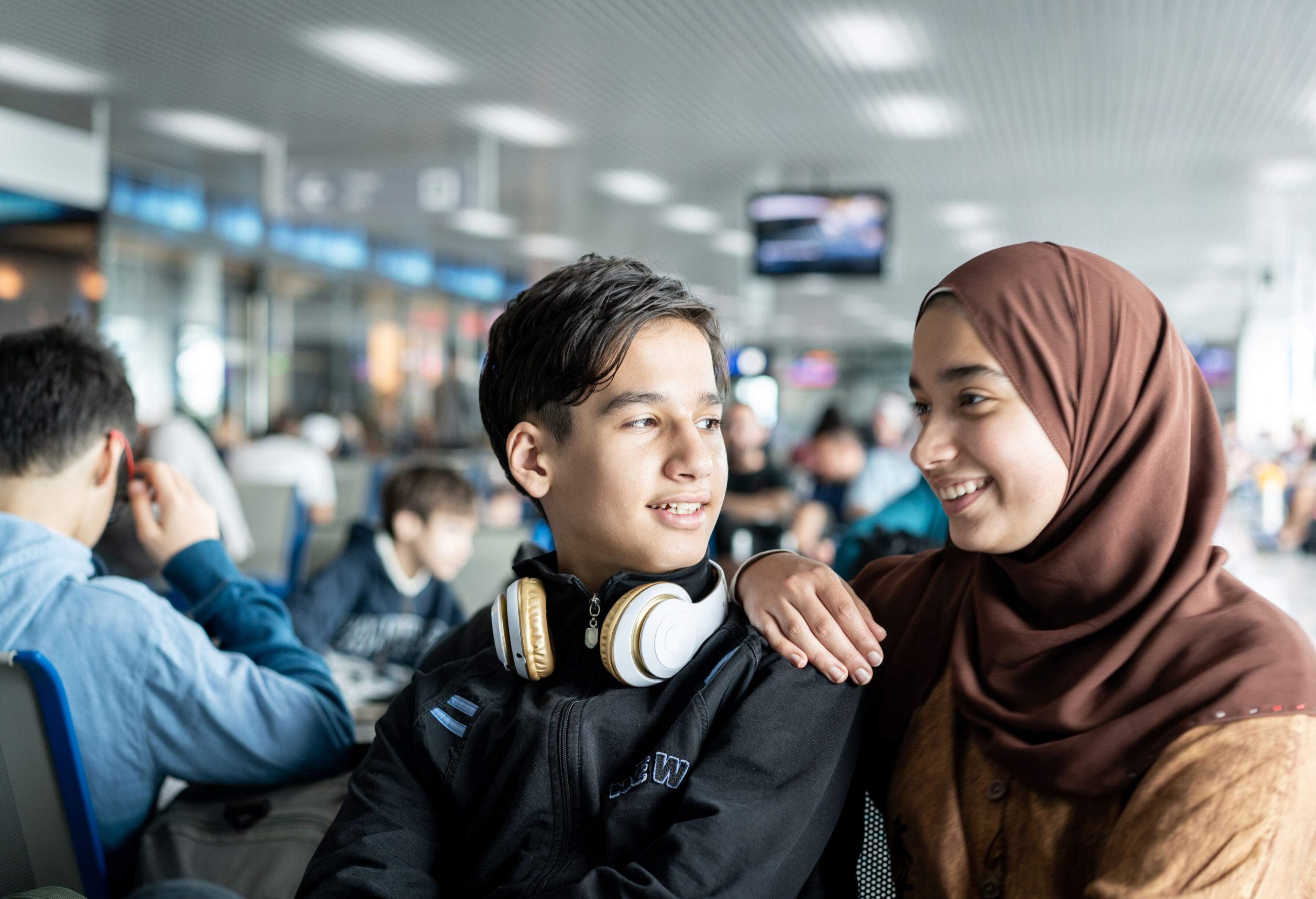 Two teenagers sitting in an airport terminal.