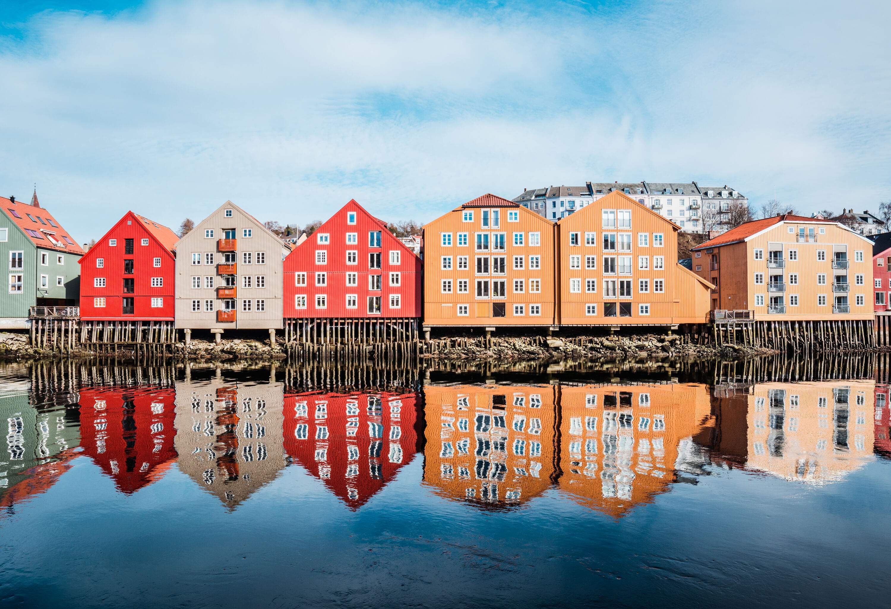 A row of colourful buildings reflected on the glassy water's surface.