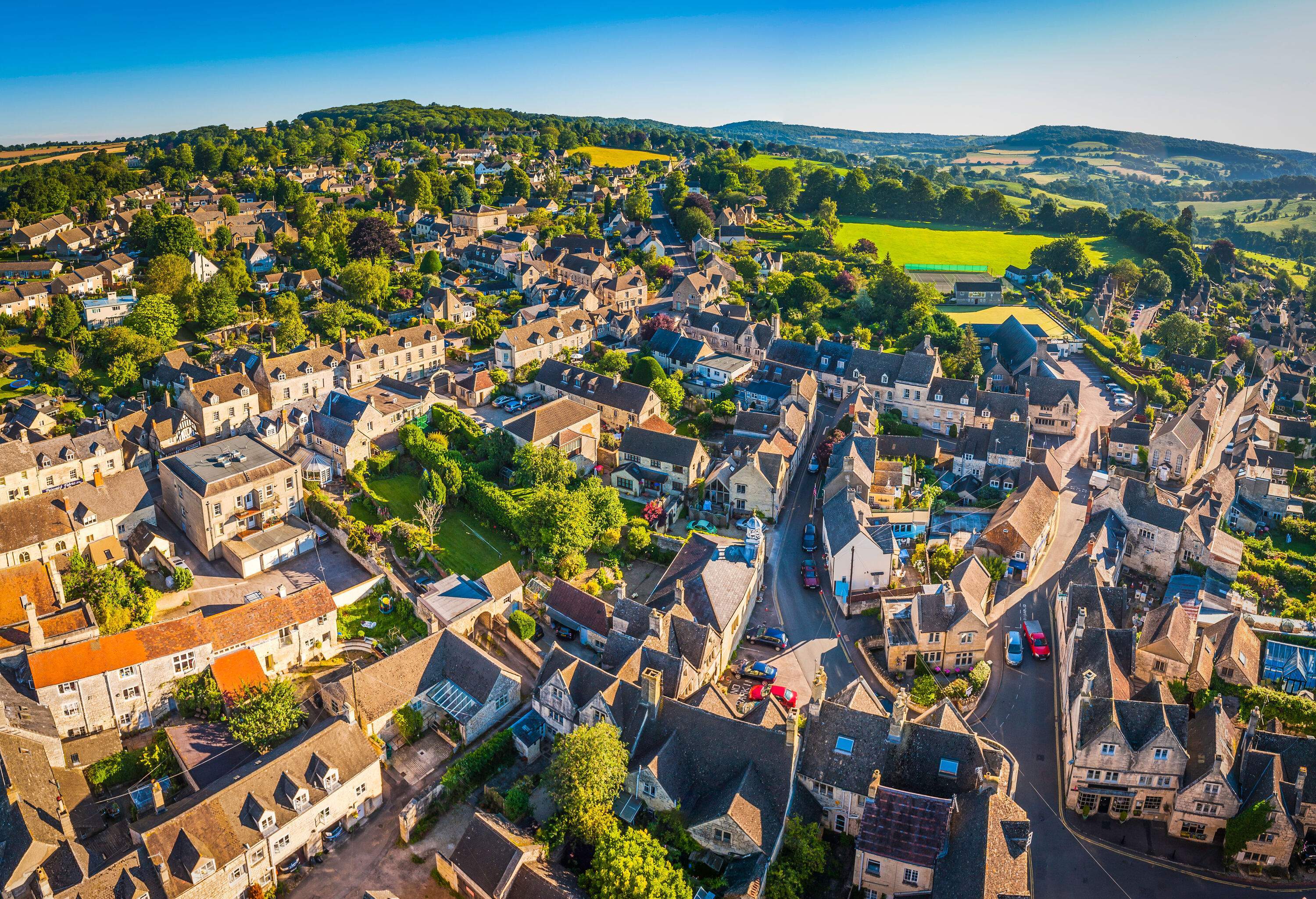 Urban setting of limestone houses and streets dotted with small green spaces and a sizable open field.