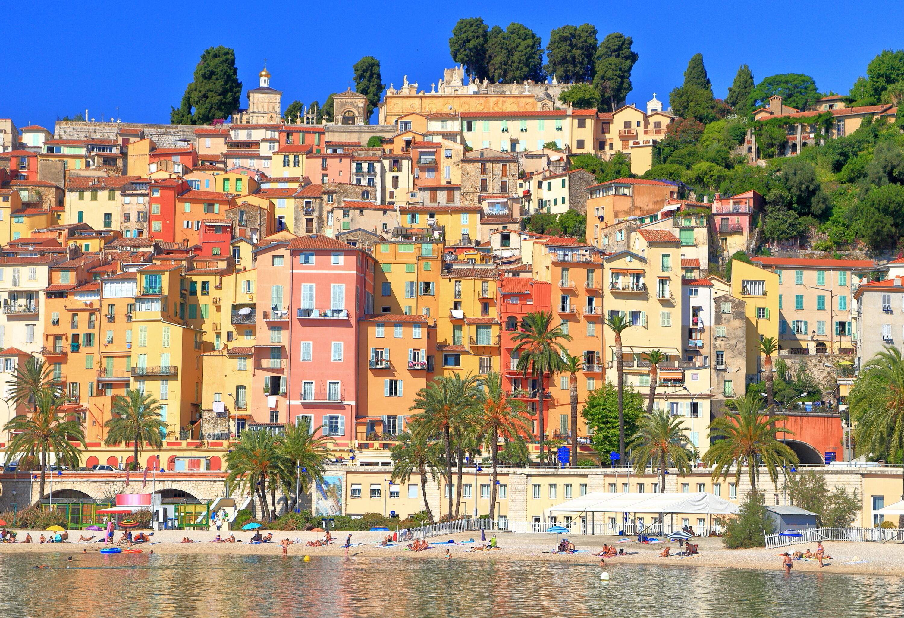 A picturesque medieval town by the beach with colourful buildings situated on a hill.