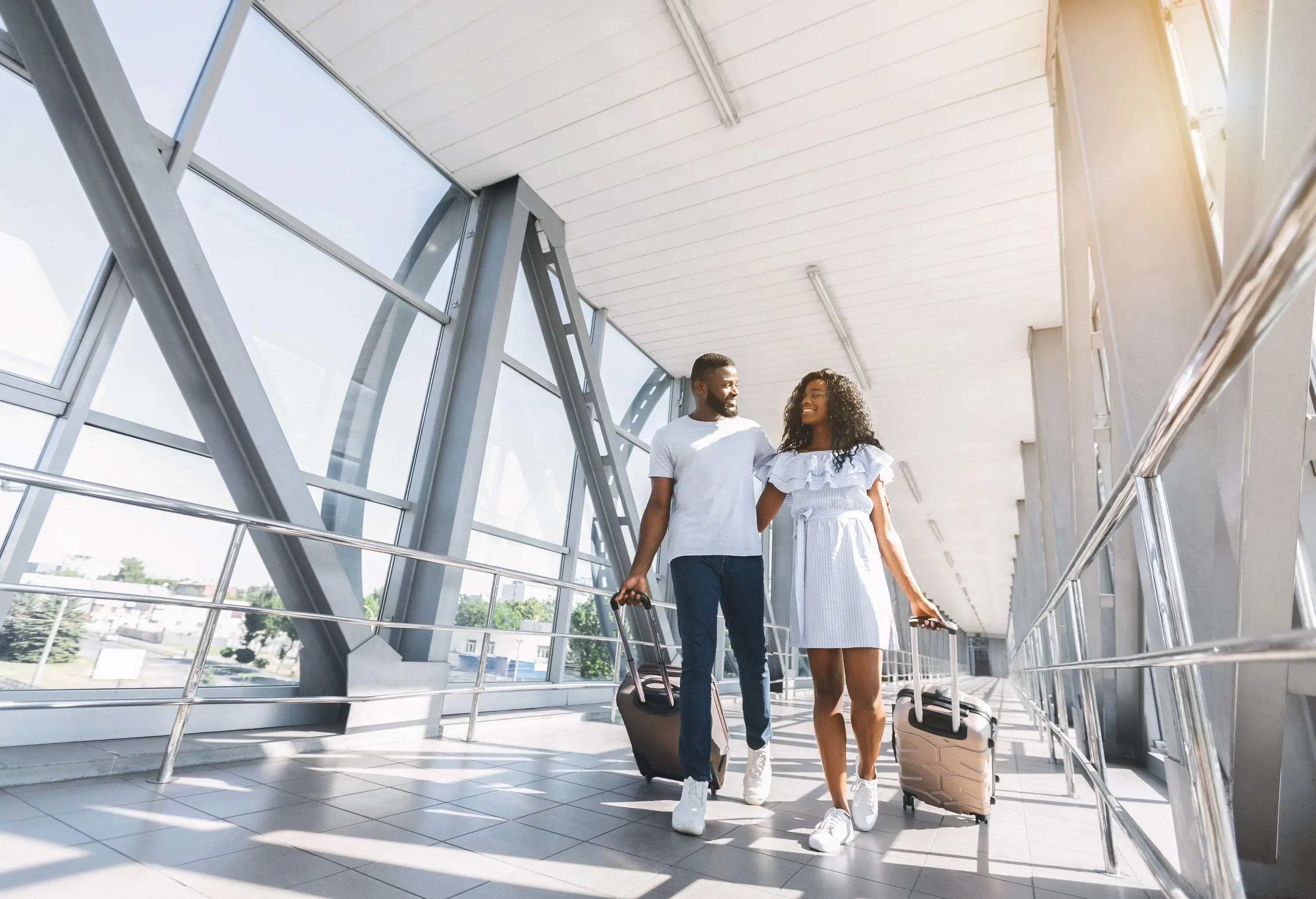 A couple walking through an airport with their luggages.