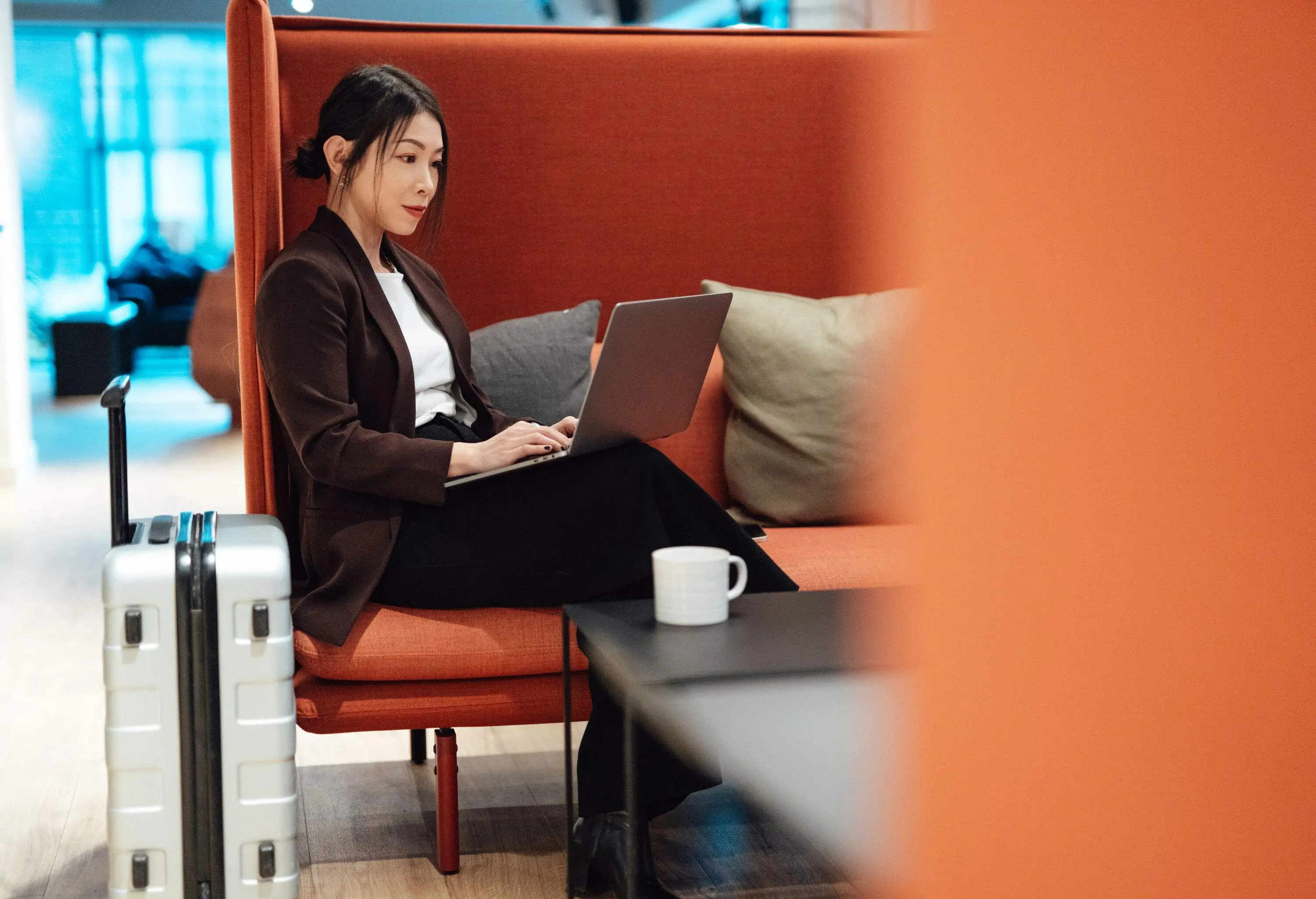 Business woman doing checking emails with smartphone while sitting at airport lounge, getting ready to depart. Young woman on business trip.