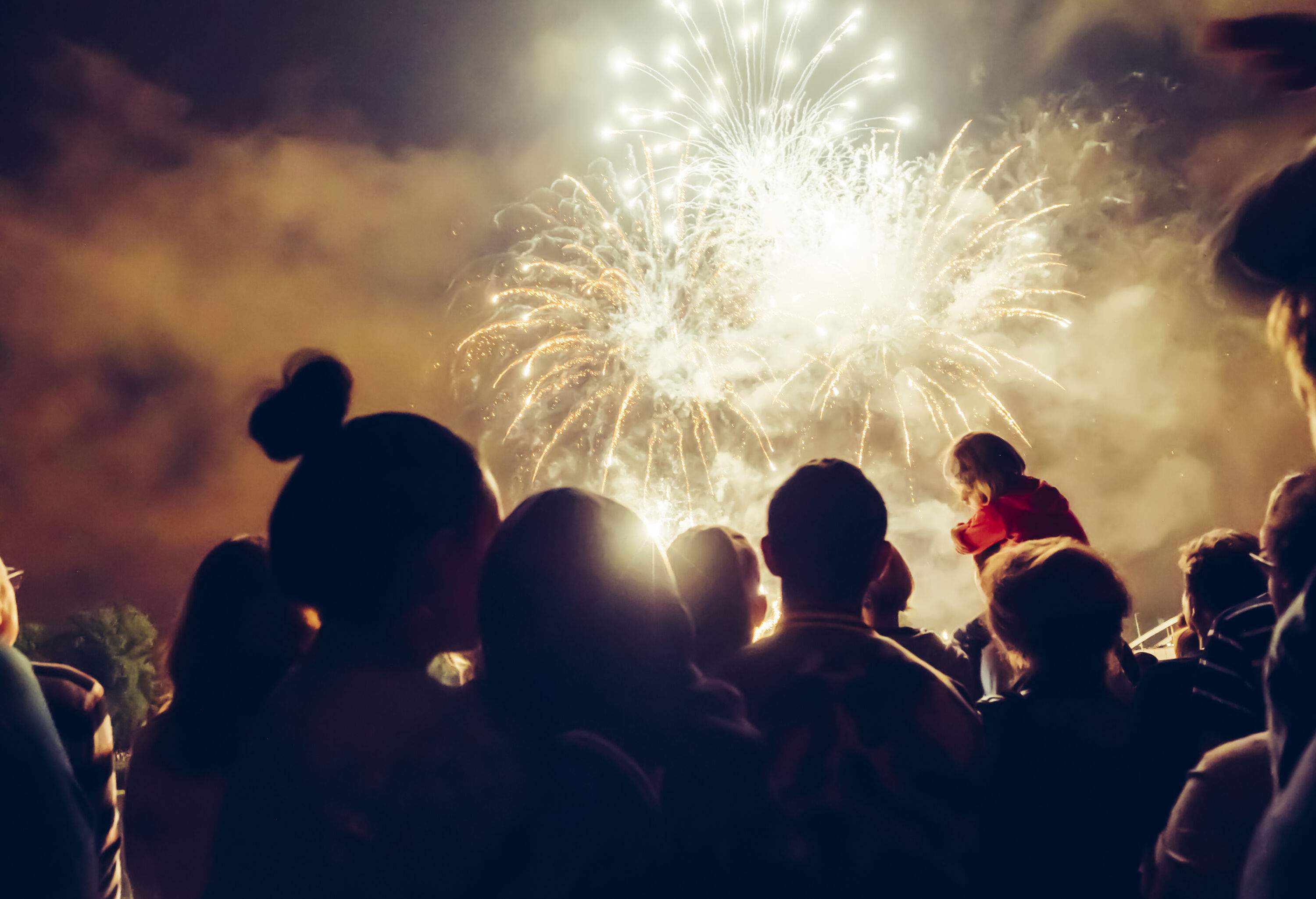 Silhouette of people watching the exploding fireworks in the sky.