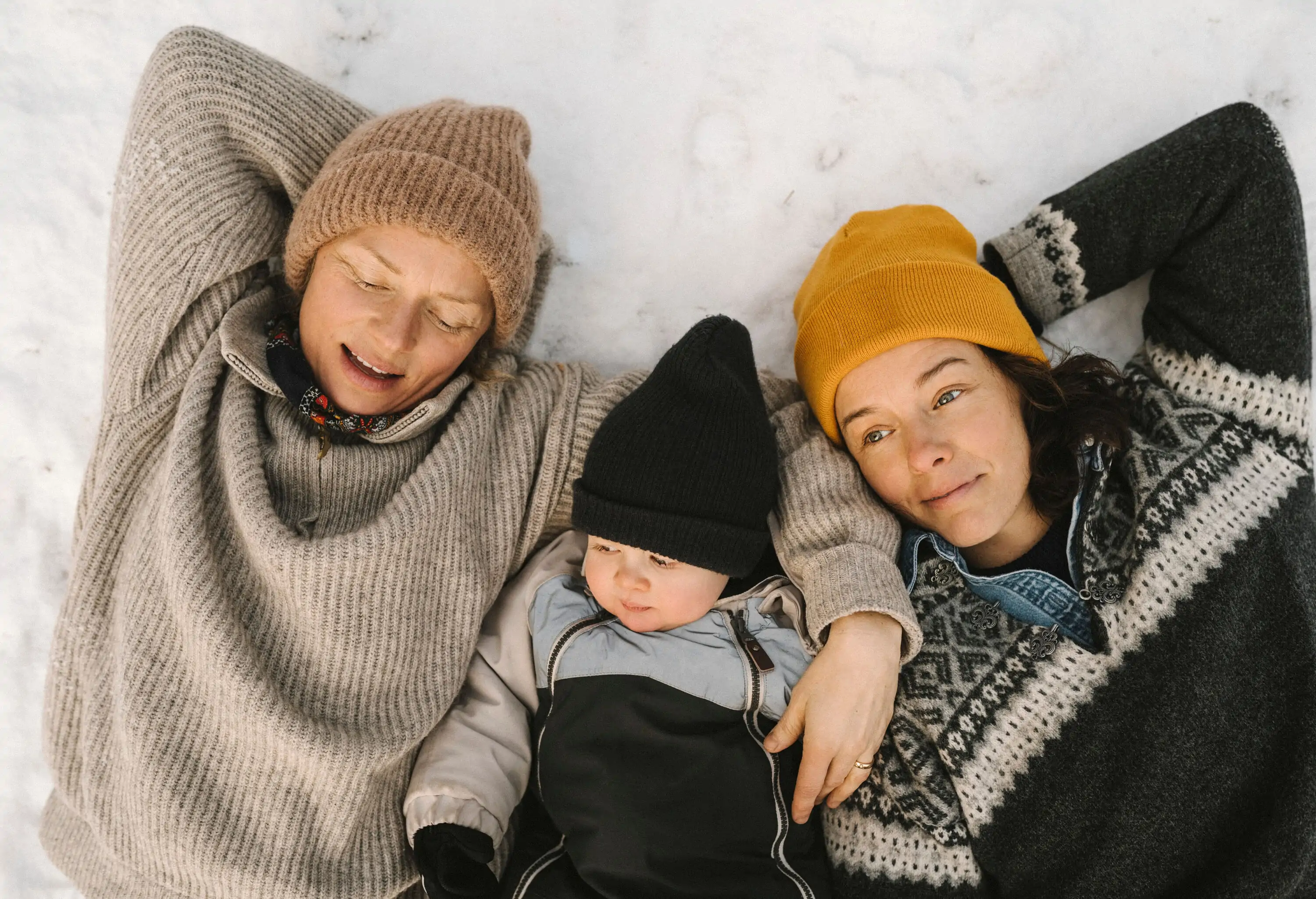 a family of tree laying with their winter clothes on i the snow