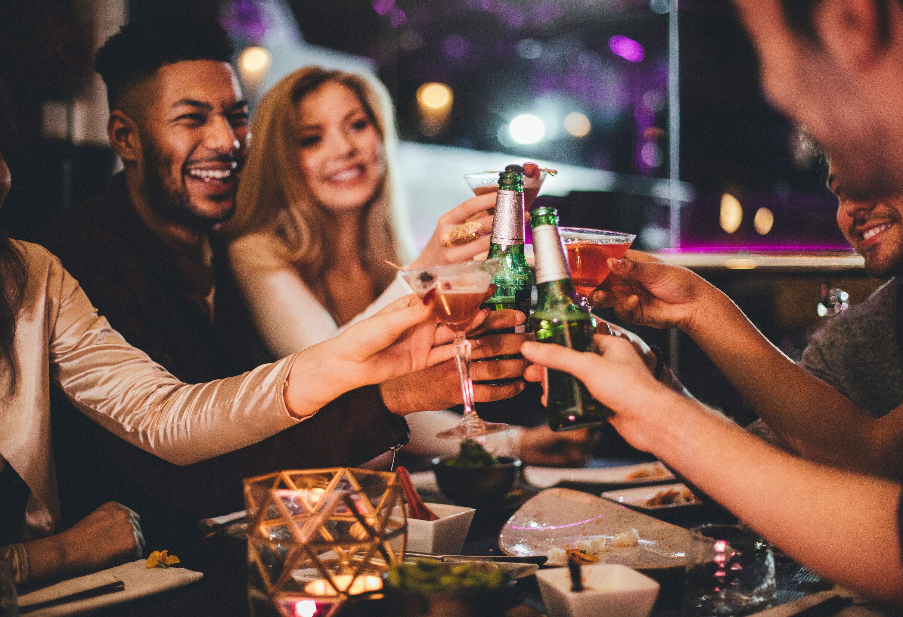 Young group of people clinking their drinks together during a night out.