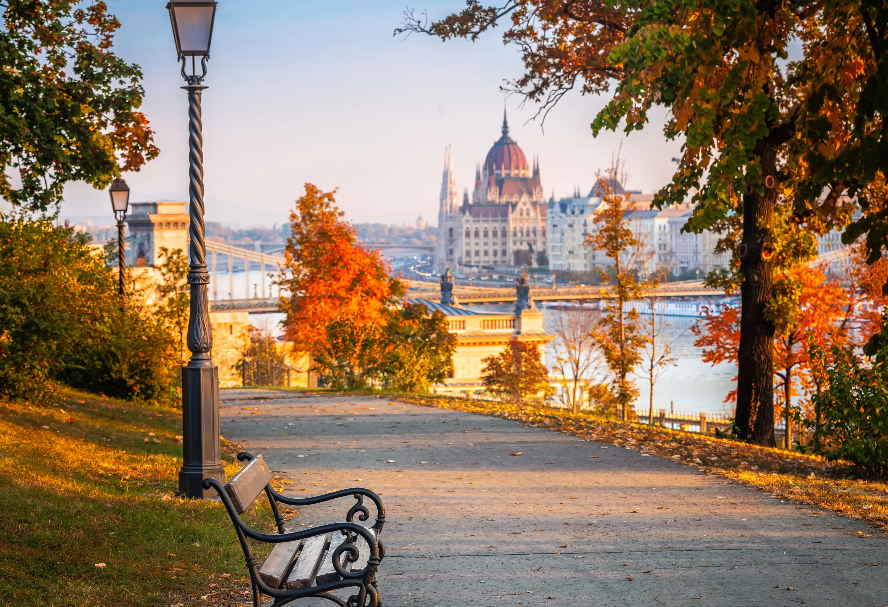 A solitary bench is situated on a path in a serene park, accompanied by a traditional lamp post.