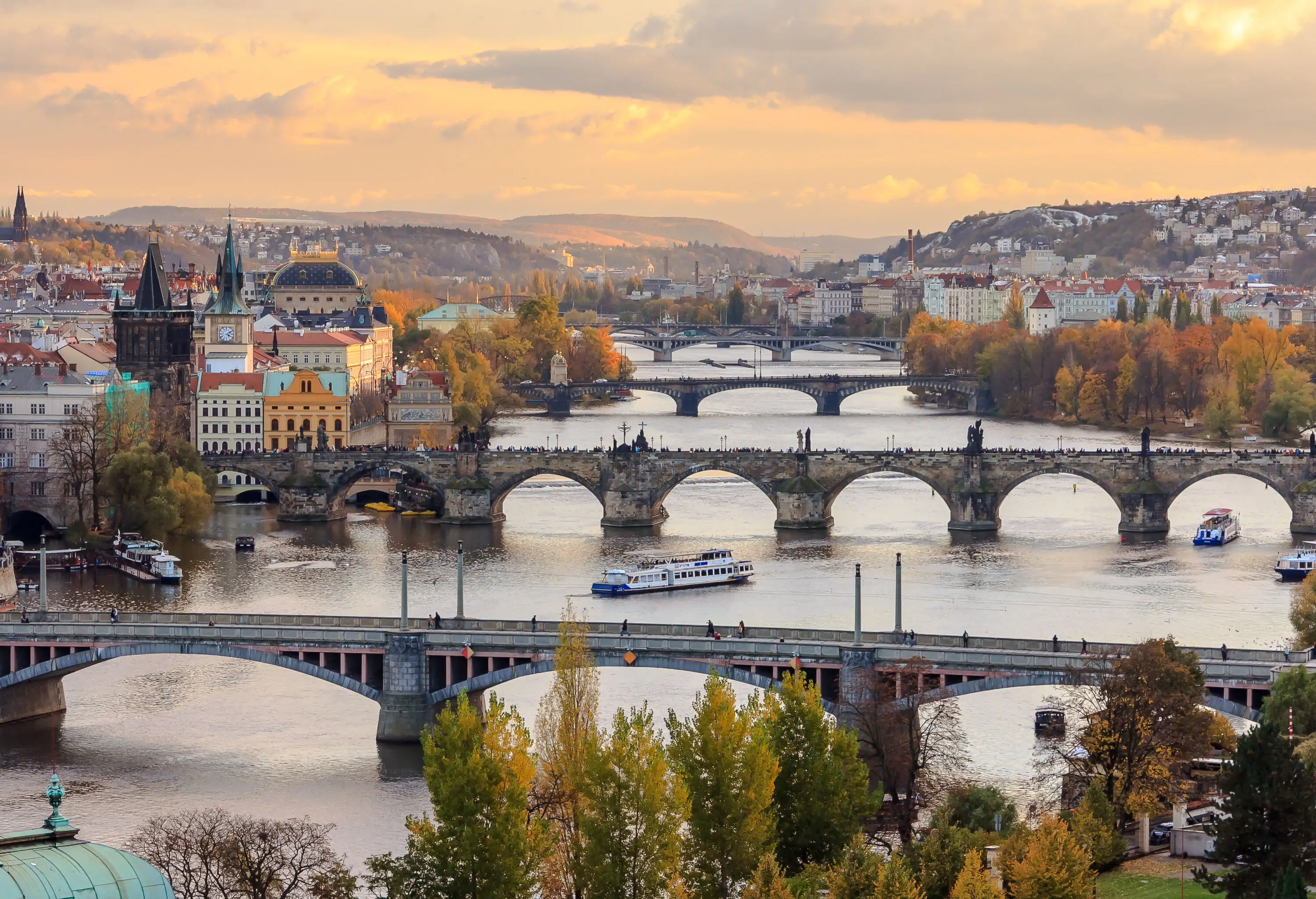 Multiple medieval stone arch bridges over a river in autumn.