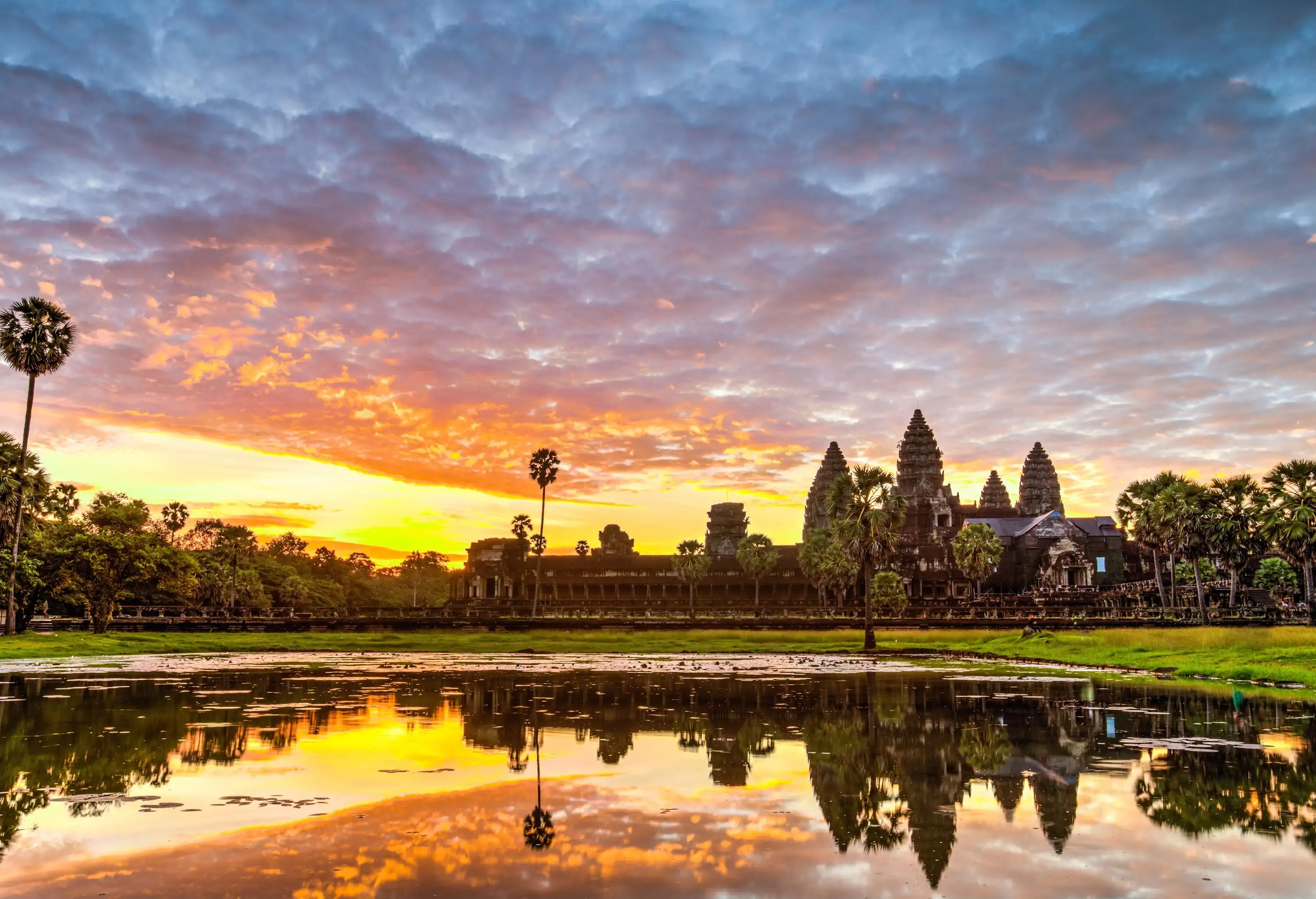 A reflective marsh displaying Angkor Wat's outline and the golden hue of light that sweeps over the sky.