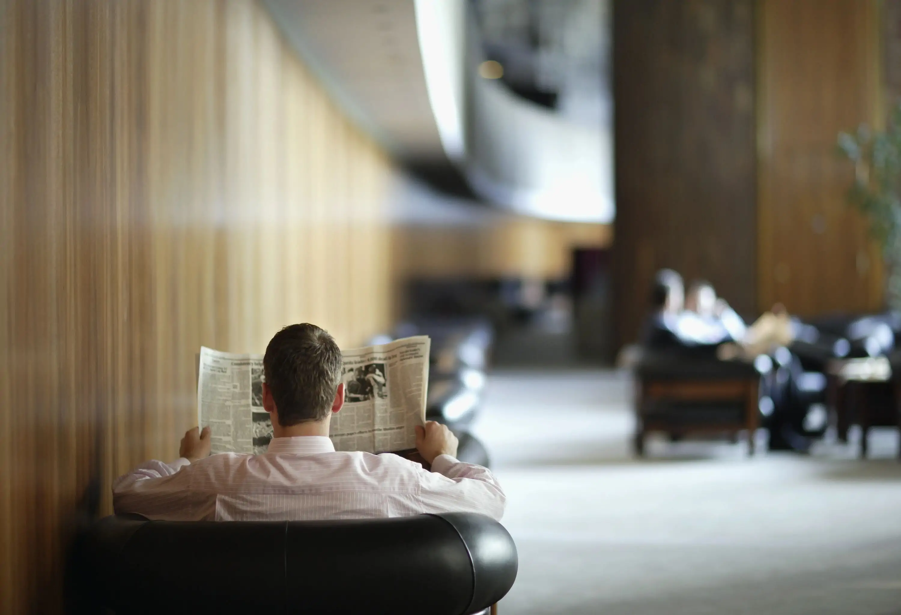 Businessman sitting in a hotel lobby reading a newspaper