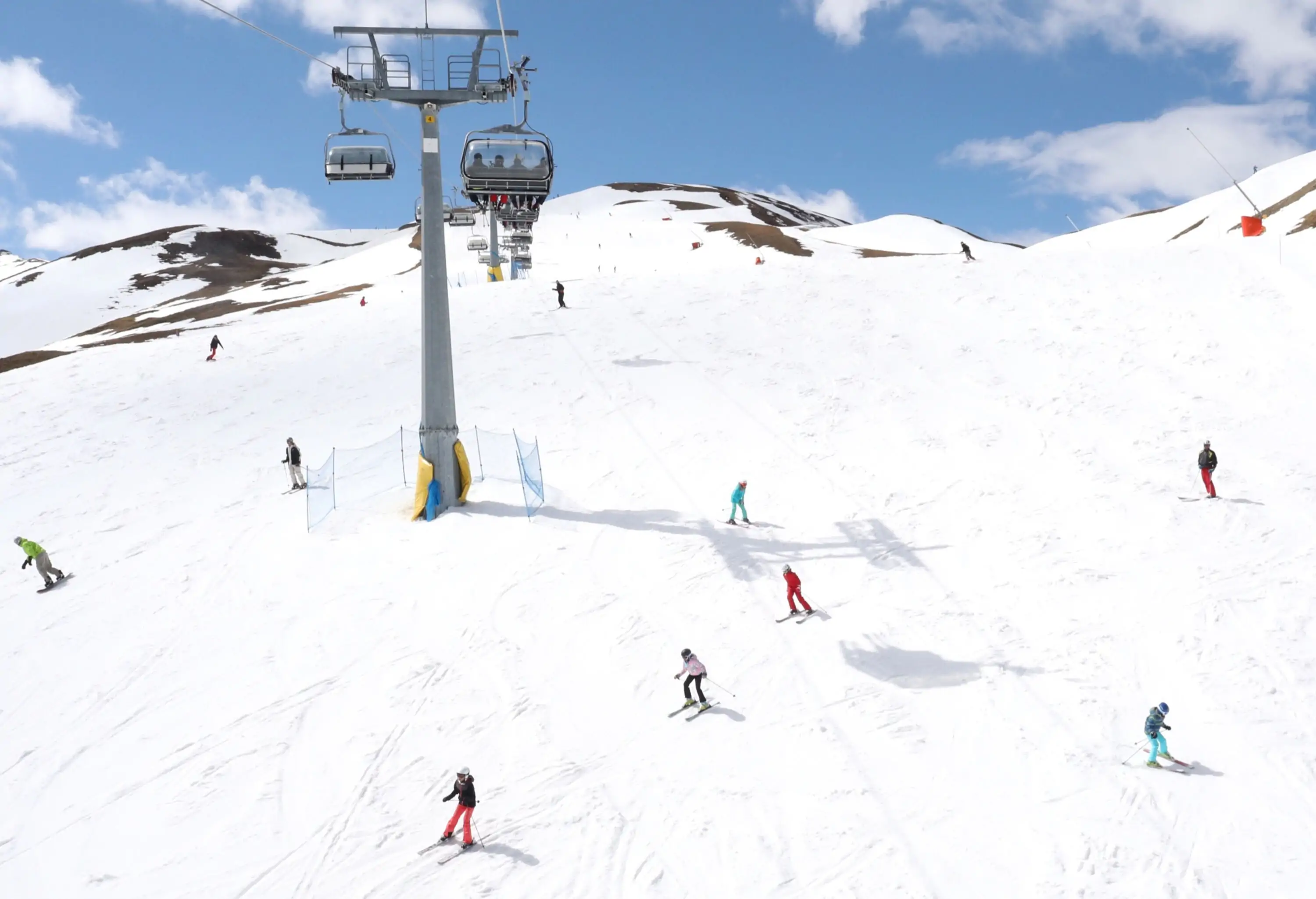 A ski slope landscape with cable cars hanging above the skiers.