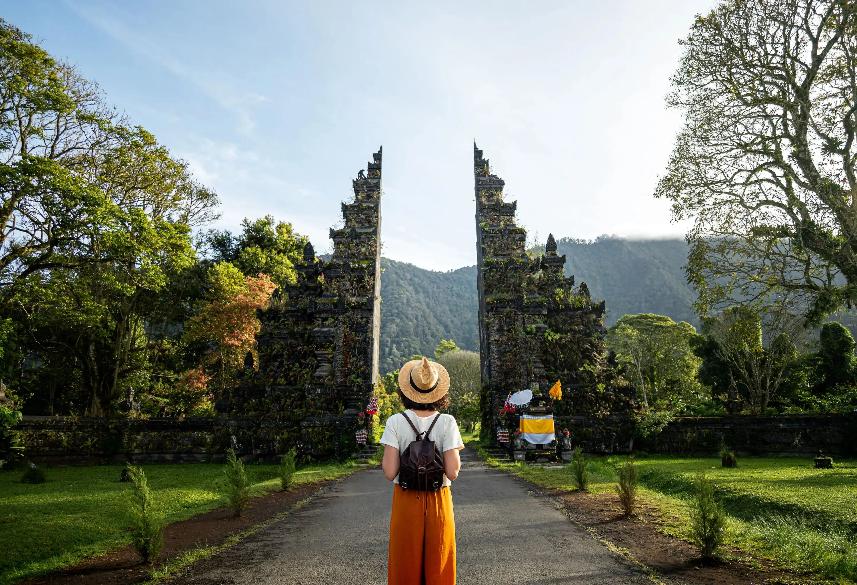 Woman tourist traveler with backpack enjoying walk through Balinese Hindu temple during vacation in Asia.